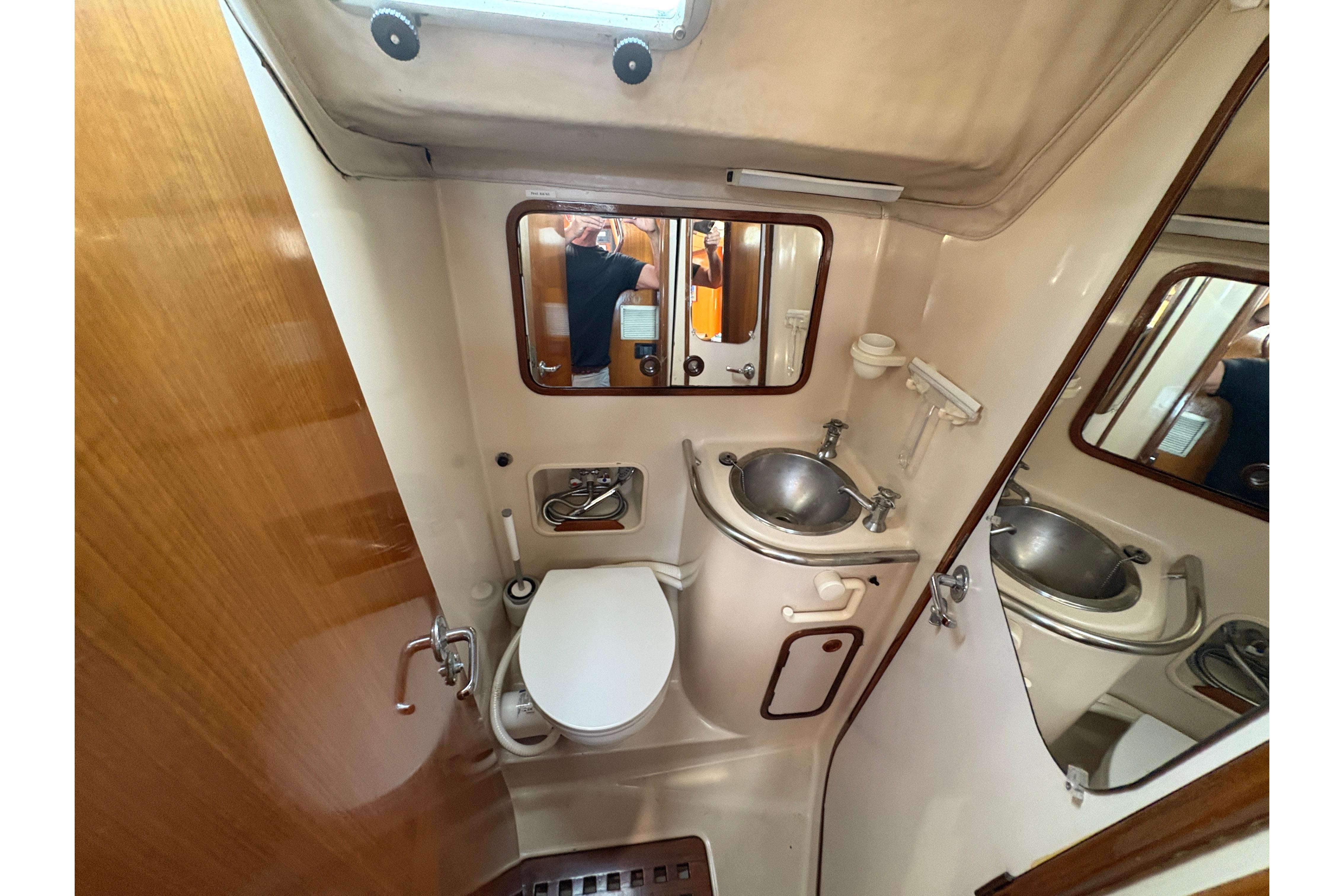 Bathroom interior of 1990 Beneteau Oceanis 500 yacht, featuring sink and toilet.