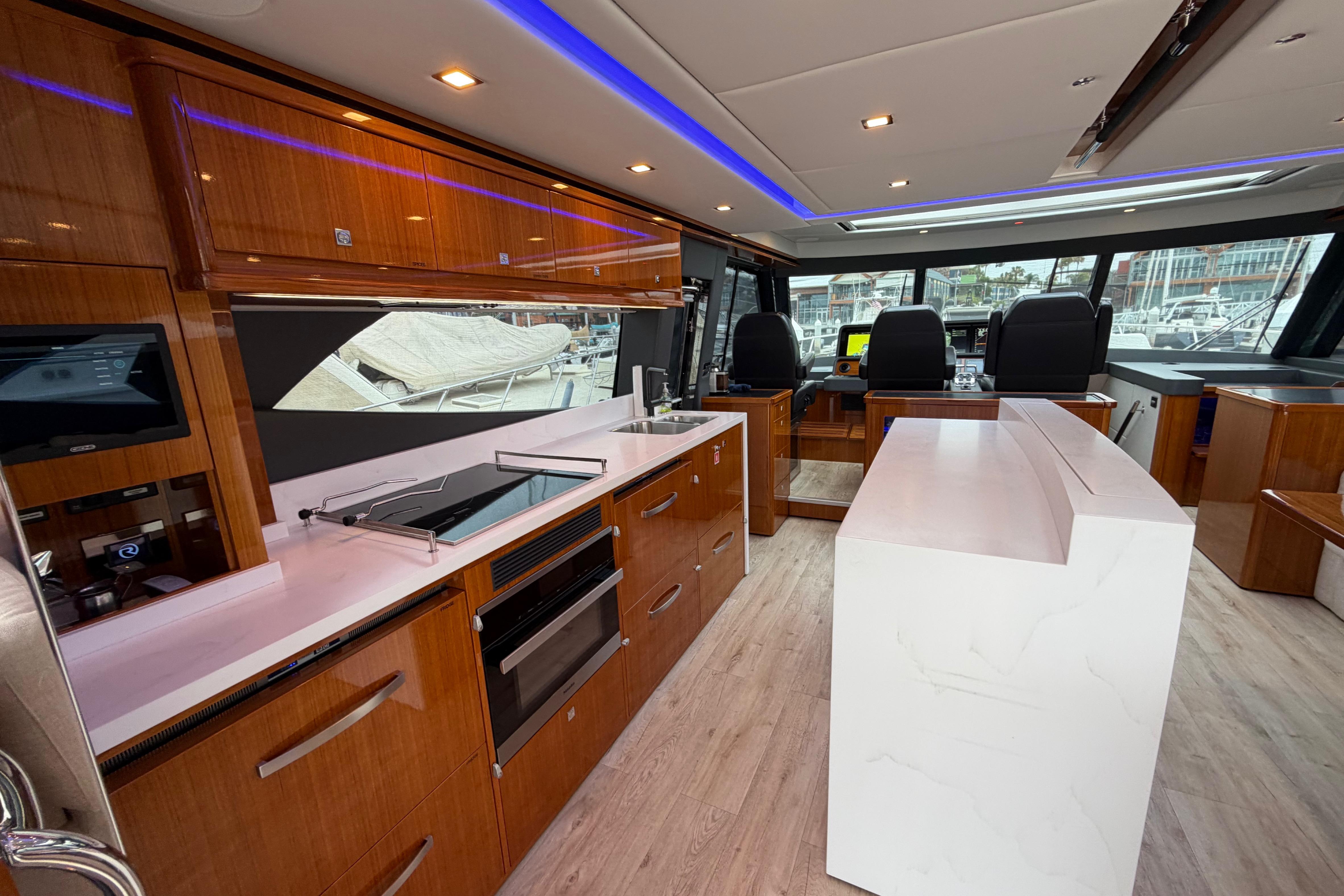 Luxurious interior of 2023 Riviera 645 SUV yacht with modern kitchen and helm station.