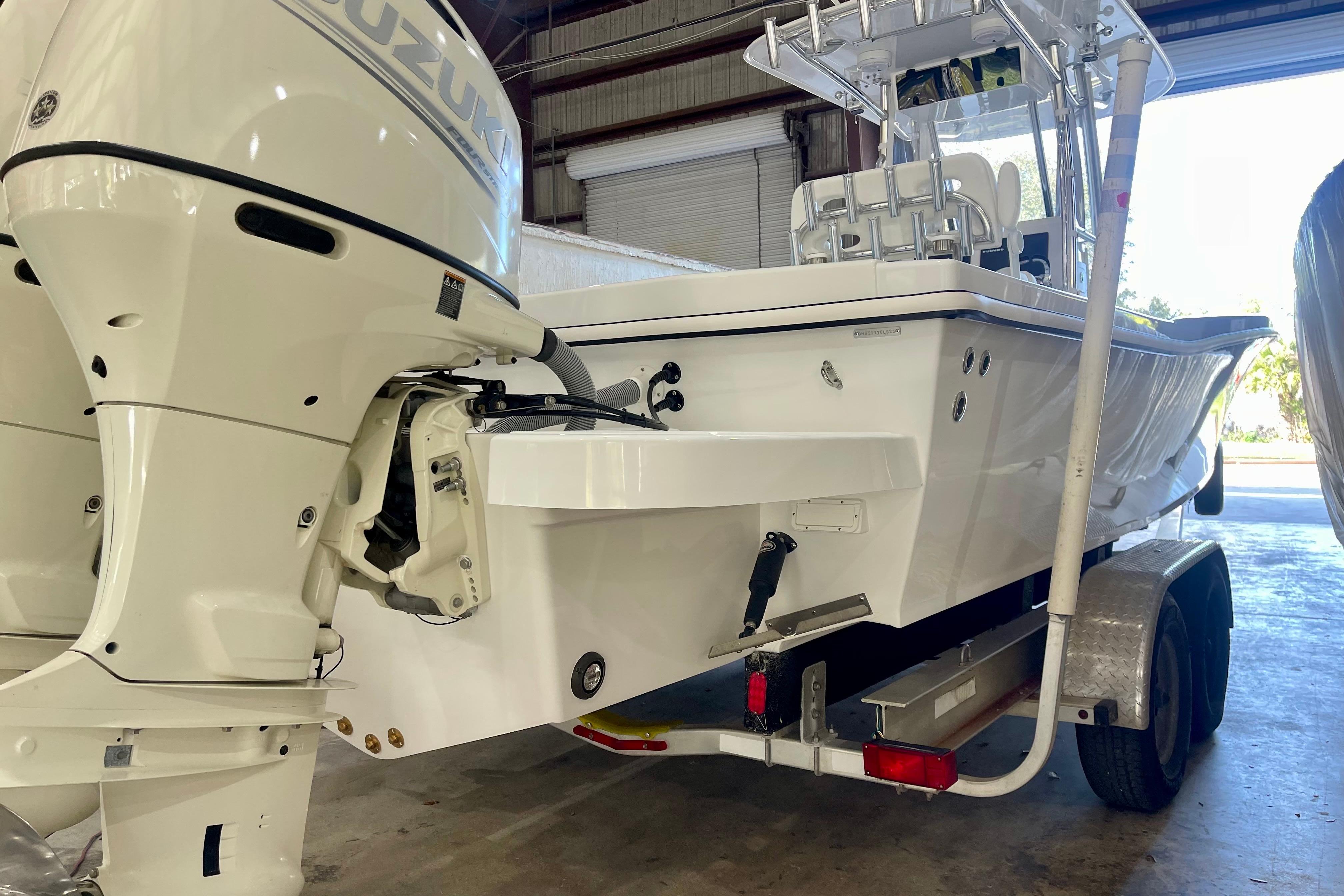 2025 Ocean Master 296 Center Console boat with Suzuki outboard engines in a garage.