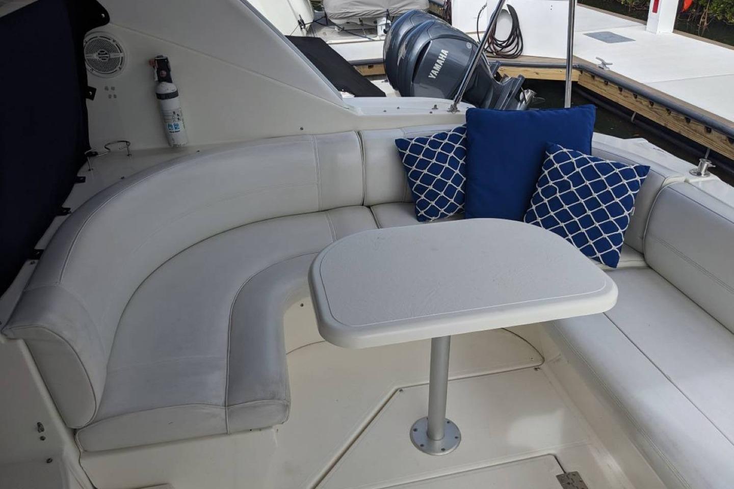 2003 Cruisers 3970 yacht interior with white seating, table, and blue decorative pillows.