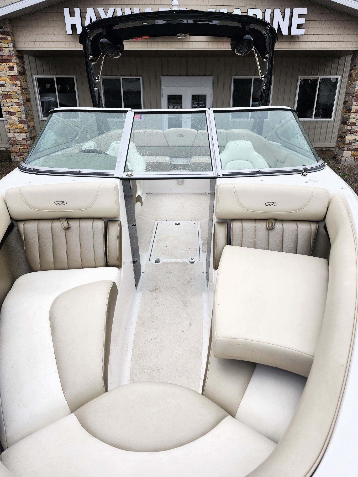 Interior view of a white boat with beige seats, in front of a building.