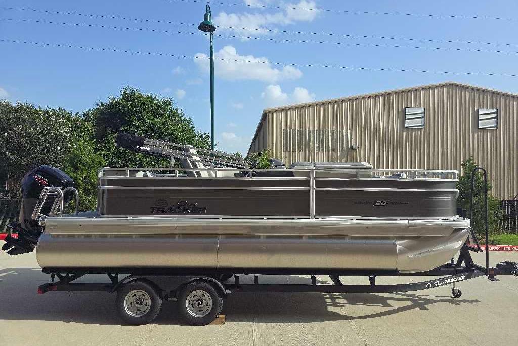 2026 Sun Tracker Fishin' Barge 20 DLX pontoon boat on trailer, outdoors.