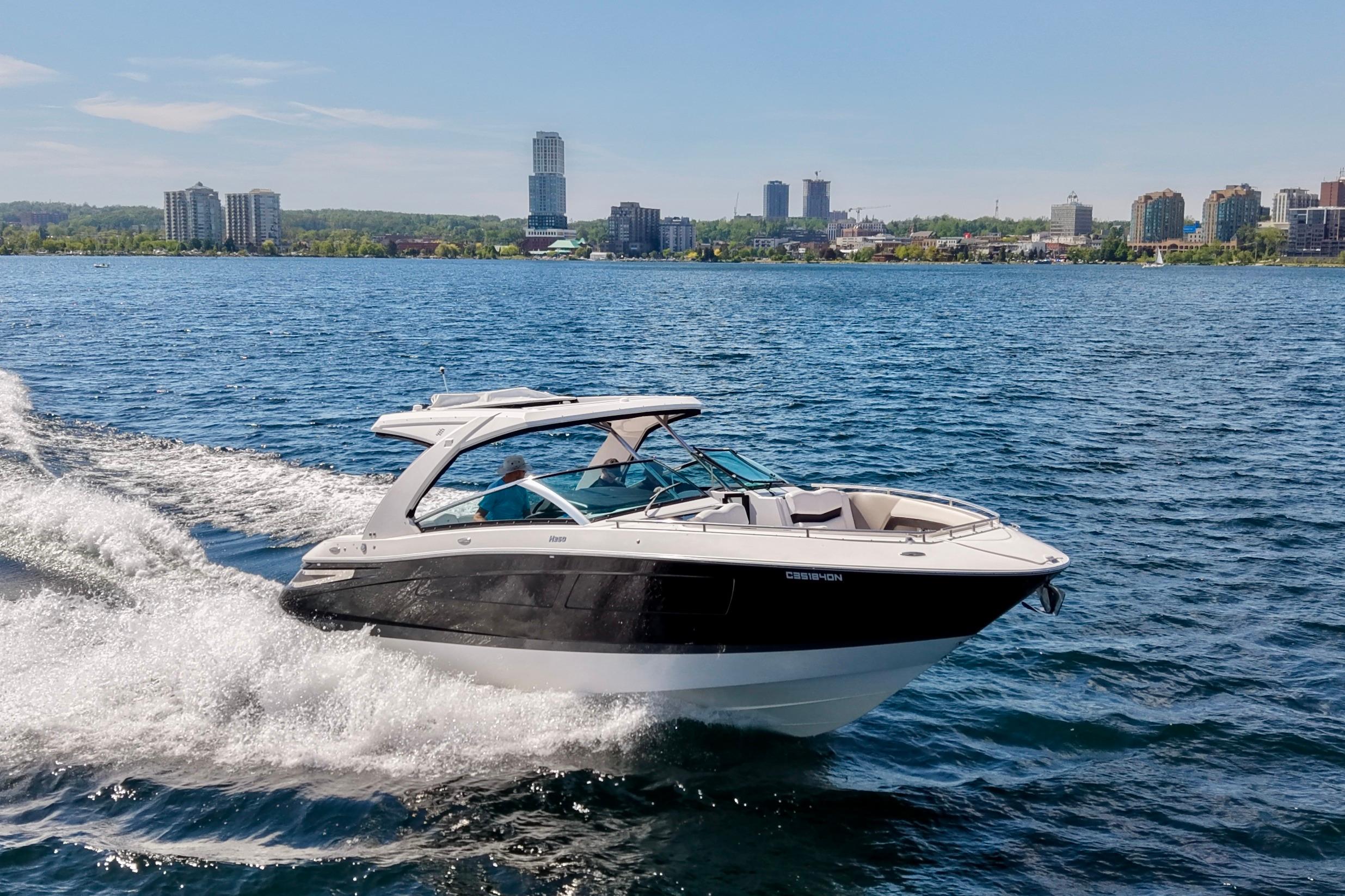 2018 Four Winns H350 boat cruising on a lake with city skyline in background.