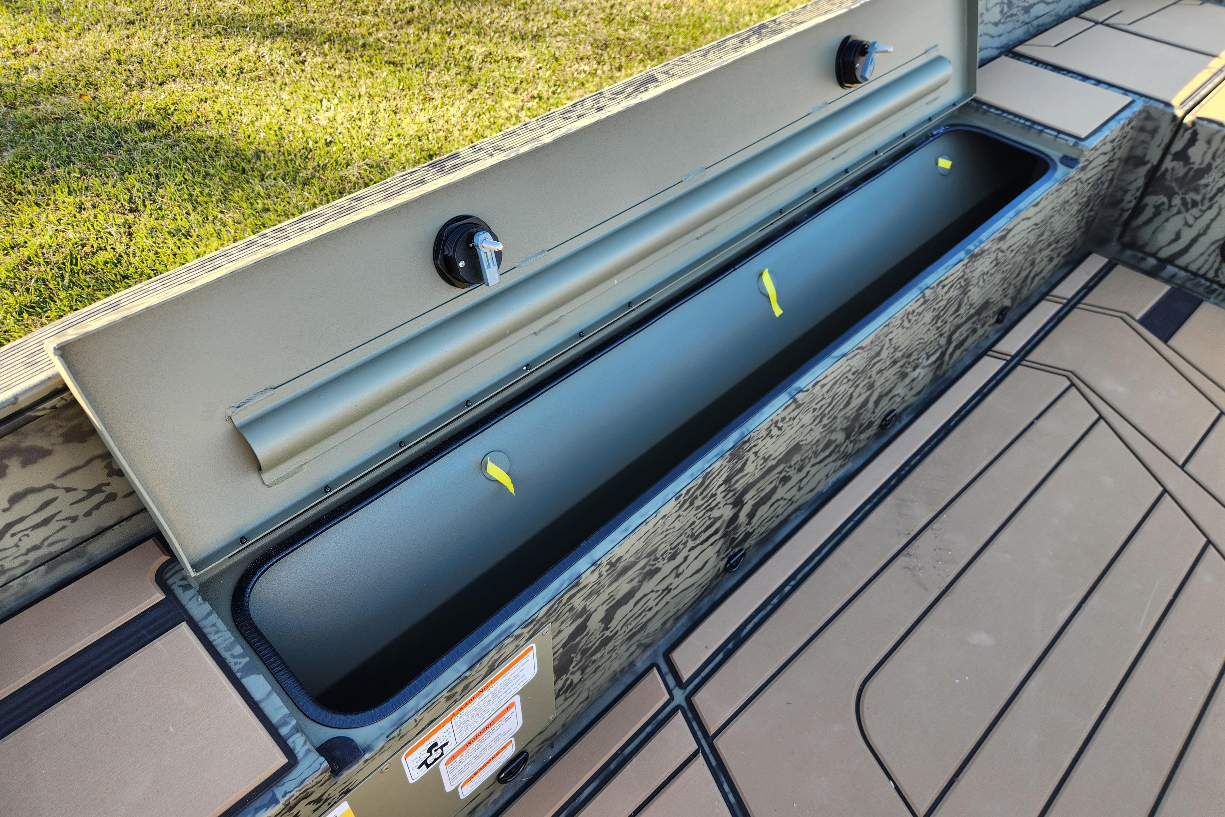 2026 Tracker Grizzly 1756 T Marsh boat storage compartment, open and empty, on a sunny day.