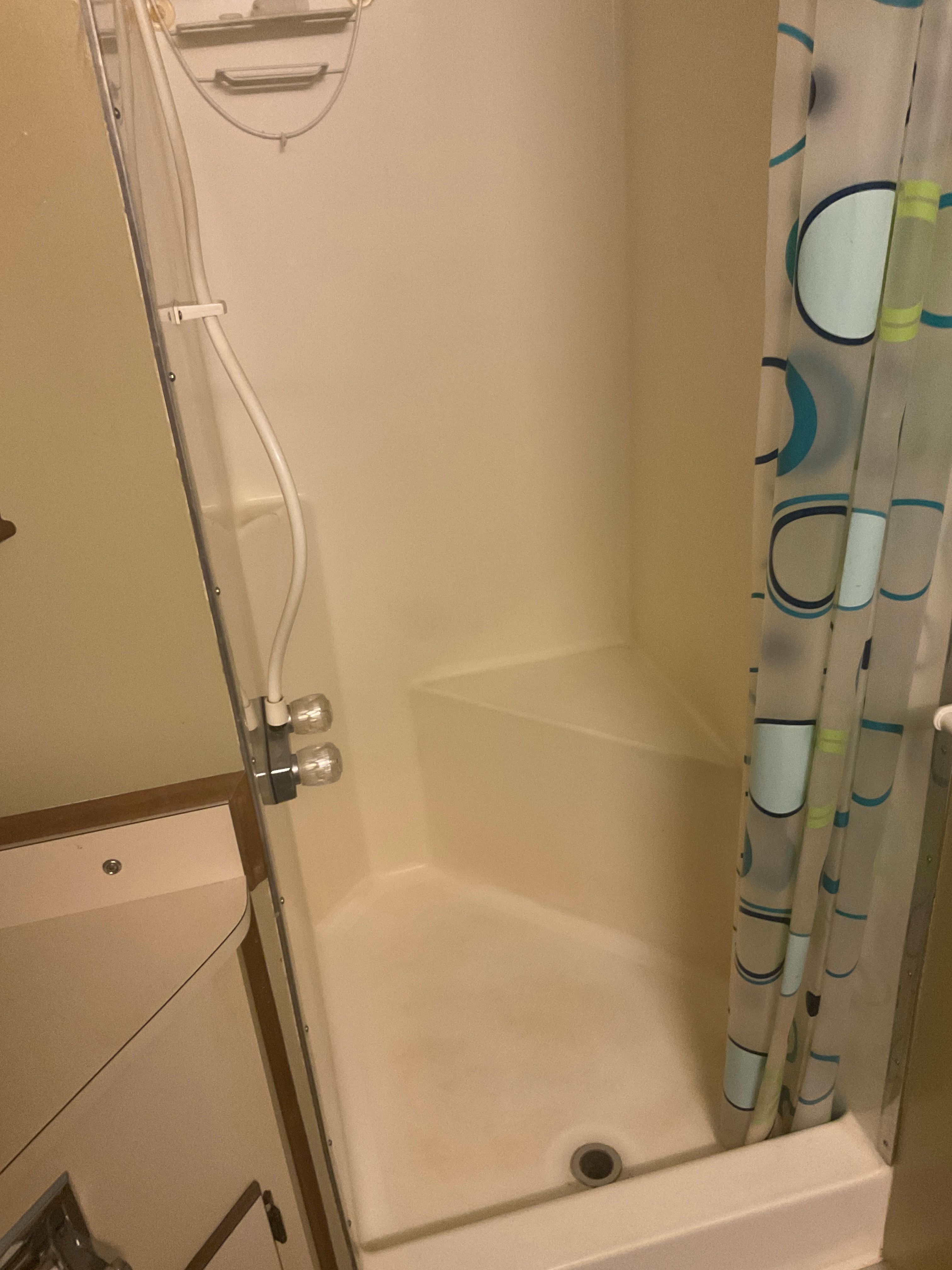 Shower stall with curtain and seat in a boat bathroom.