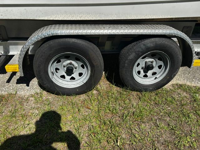Close-up of a boat trailer with two tires on grass.