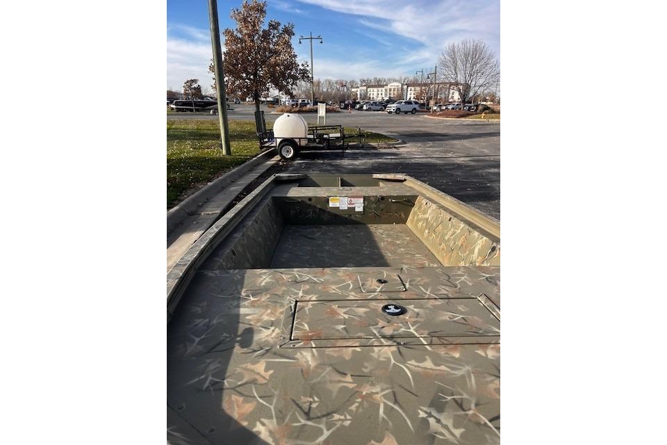 2025 Tracker Grizzly 1648 Jon boat with camouflage design in a parking lot.