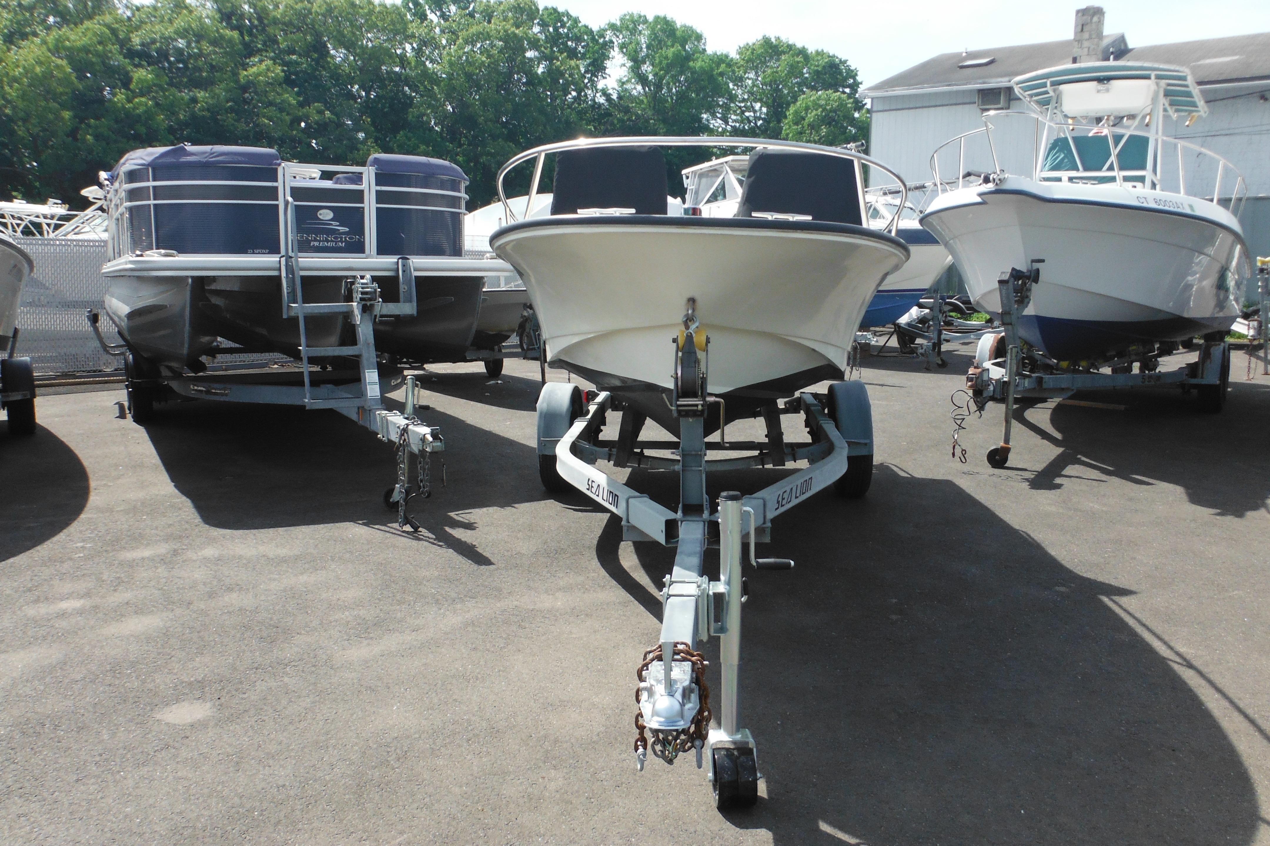 1991 Boston Whaler 16 SL boat on trailer, parked between two other boats.