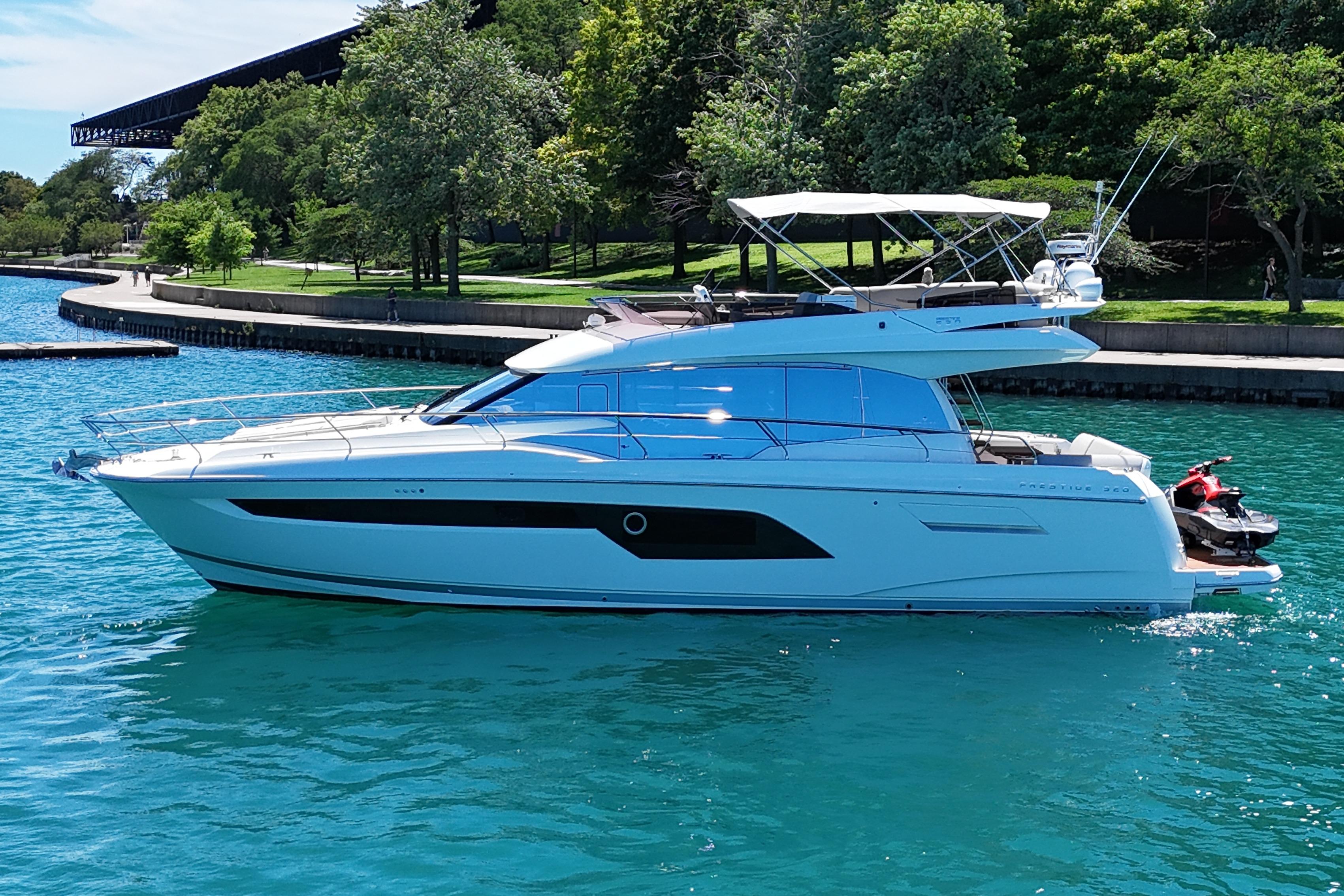 Luxury 2022 Prestige 520 yacht cruising on clear blue water near a lush shoreline.