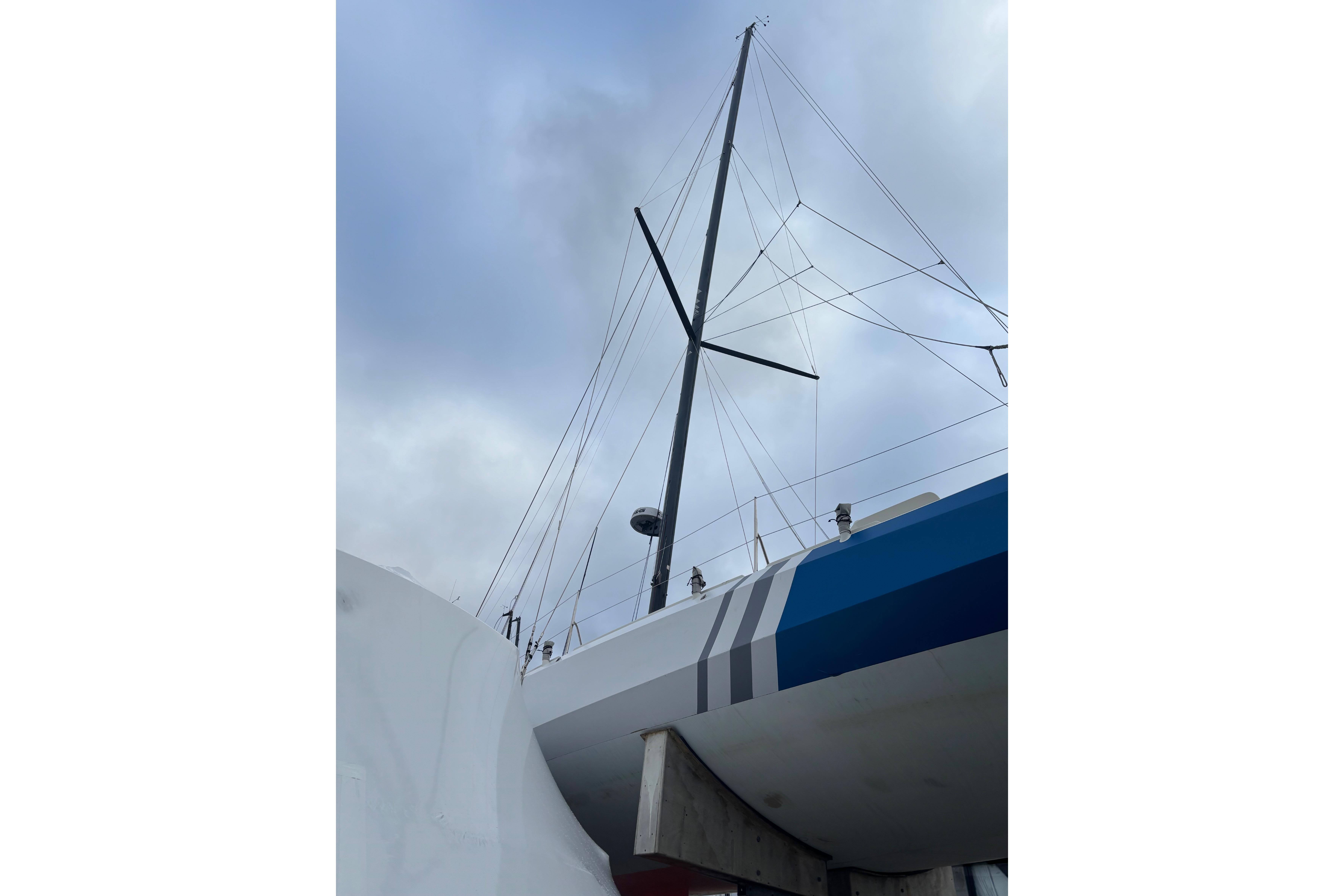Sailboat Class 40 Mach 40.3, 2015 model, with tall mast against cloudy sky.