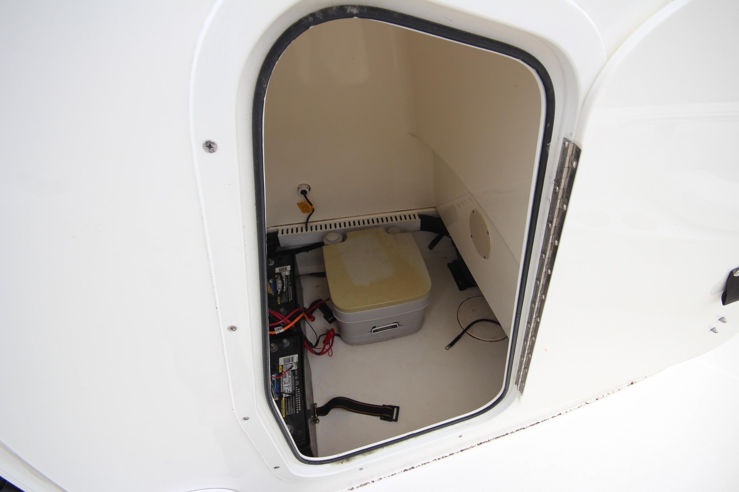 Storage compartment of a 2014 Boston Whaler 210 Dauntless boat, featuring batteries and equipment.