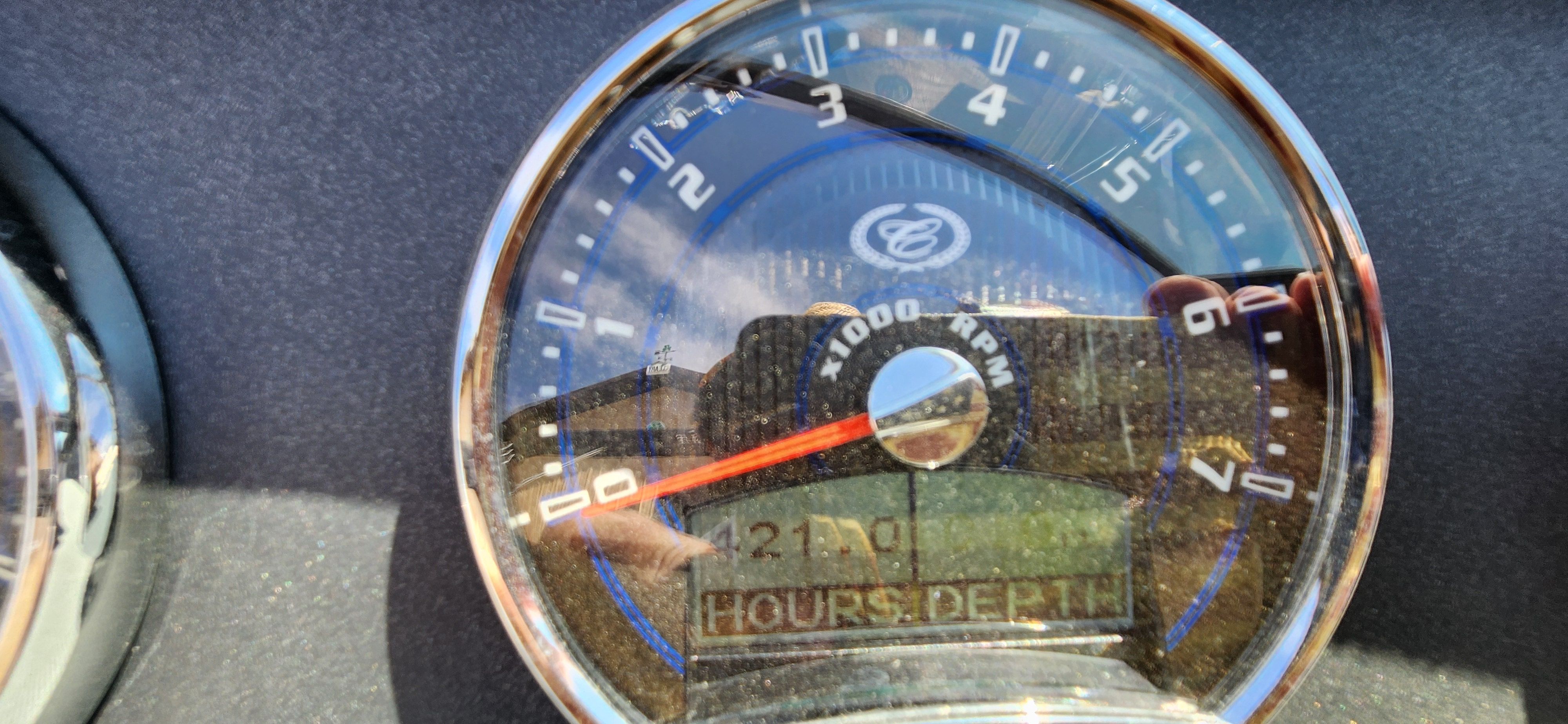 Close-up of a tachometer with reflected sky.