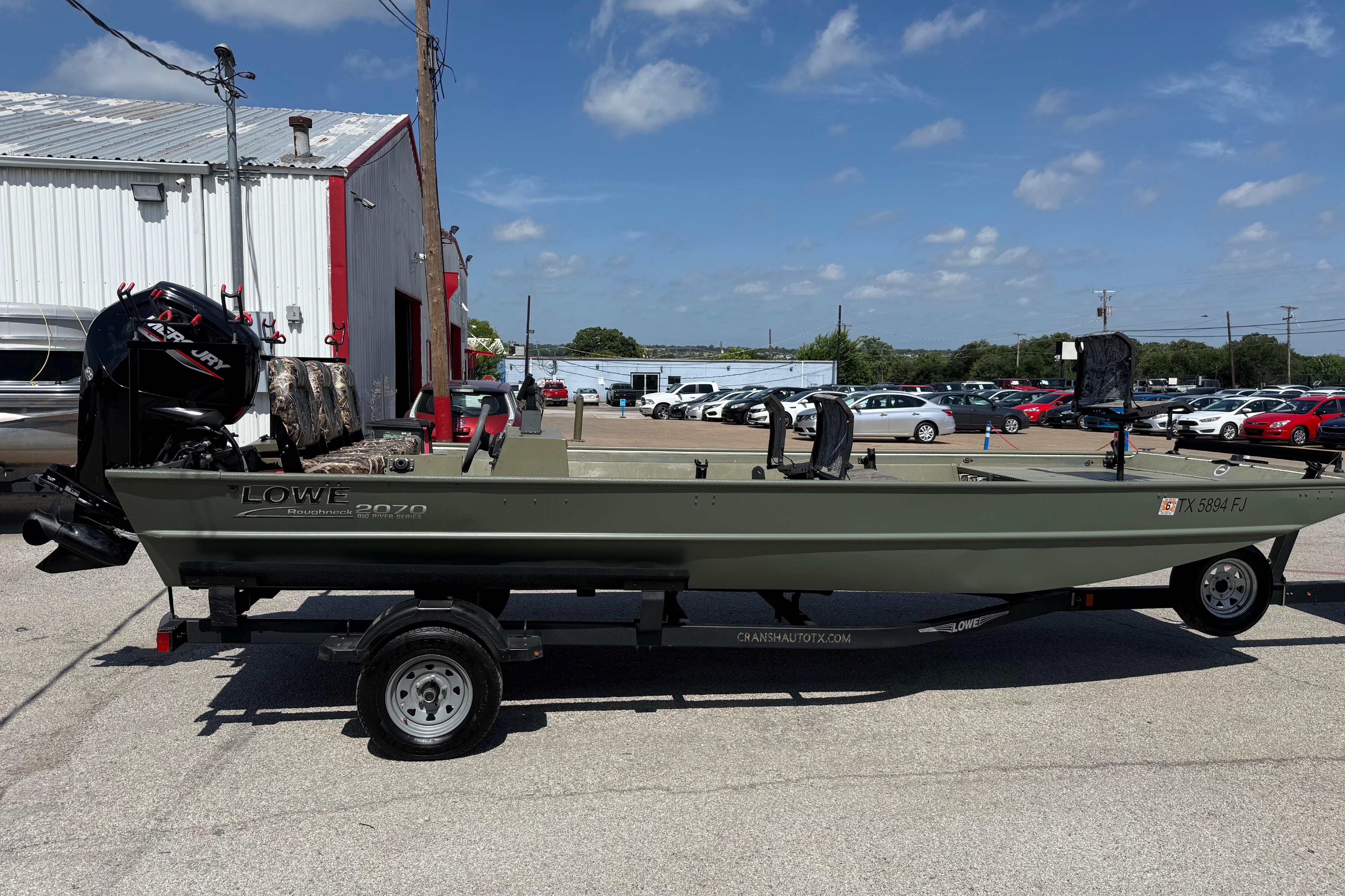 A 2020 Lowe Roughneck 2070 Big River boat on a trailer in a parking lot.