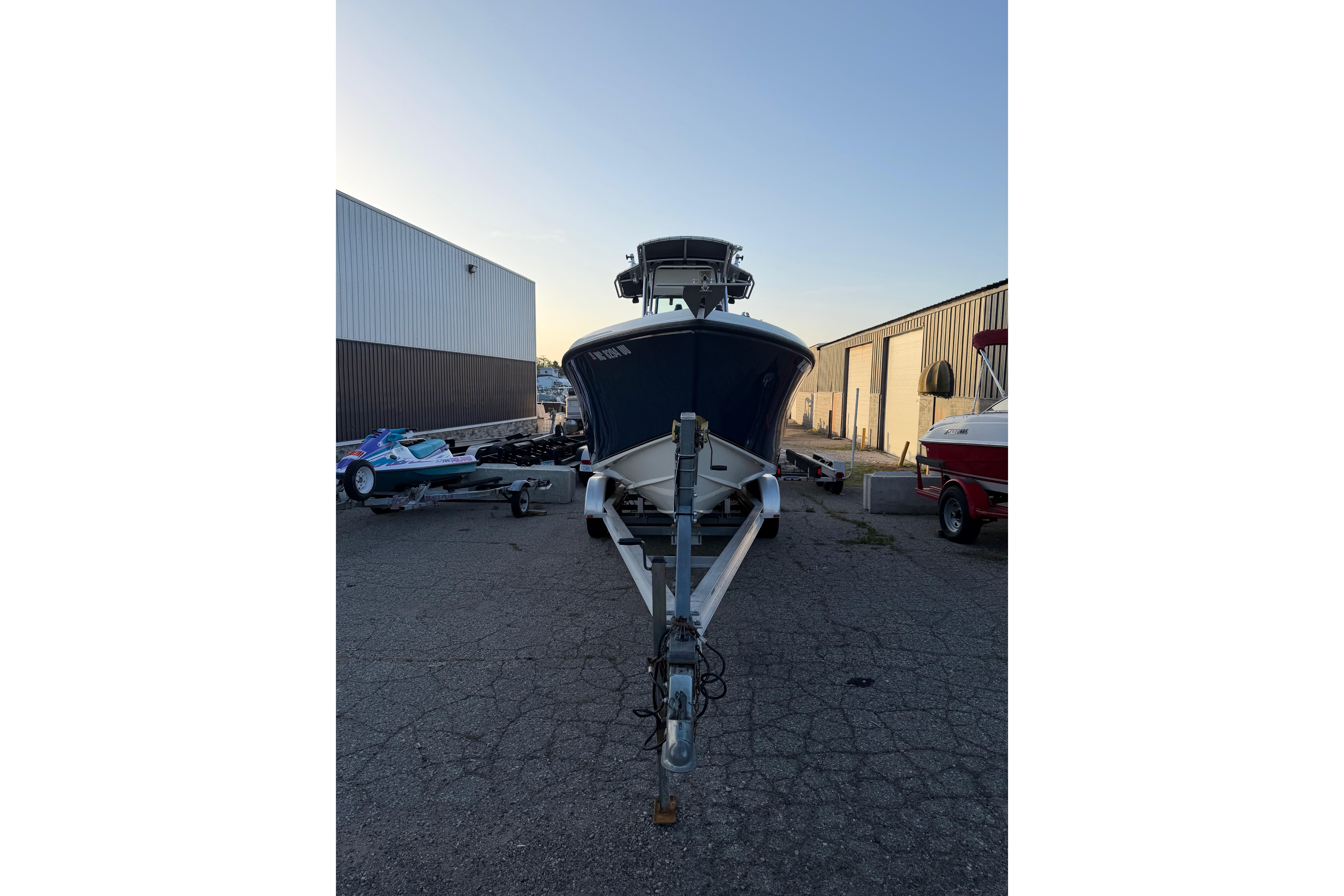 2007 Mako 234 Center Console boat on trailer, parked outdoors near warehouses.