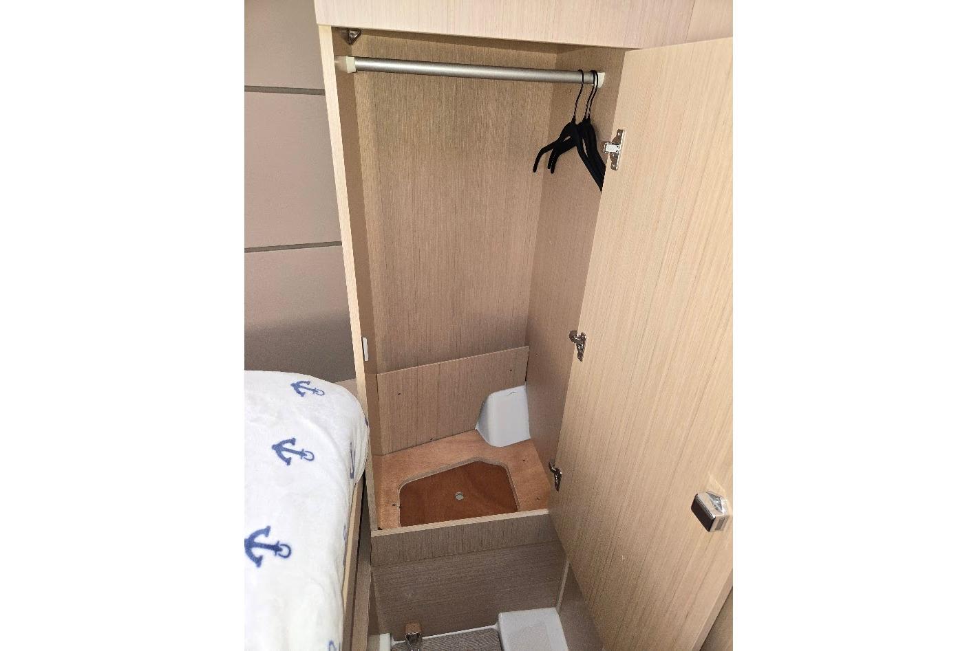 2023 Beneteau Oceanis 38.1 interior closet with hangers and wooden finish.