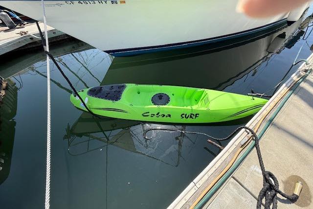 Bright green Cobra Surf kayak docked beside a Lancer 45 Motorsailer, 1982 model.