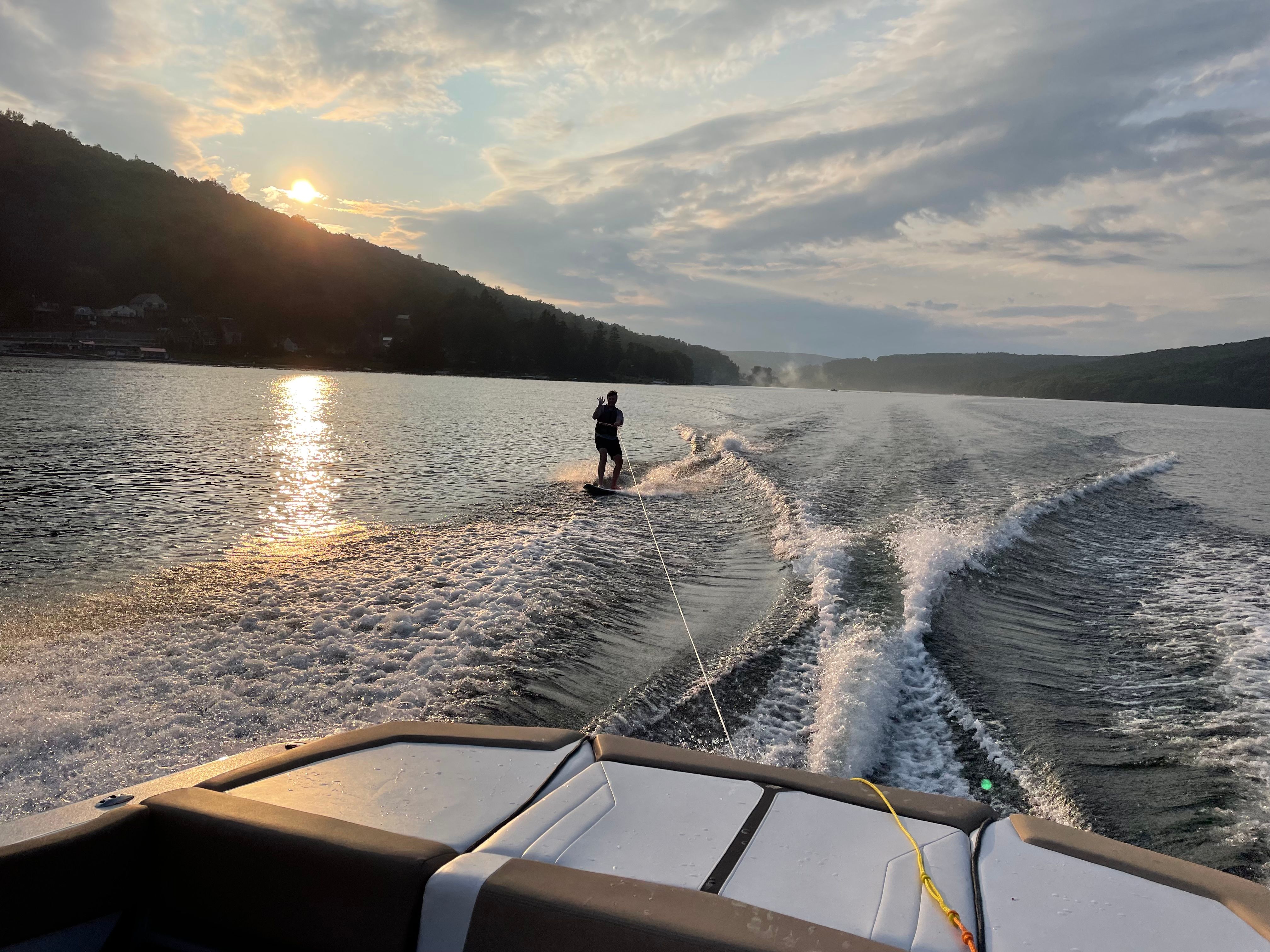 Wakeboarding behind a Four Winns H210 boat at sunset.