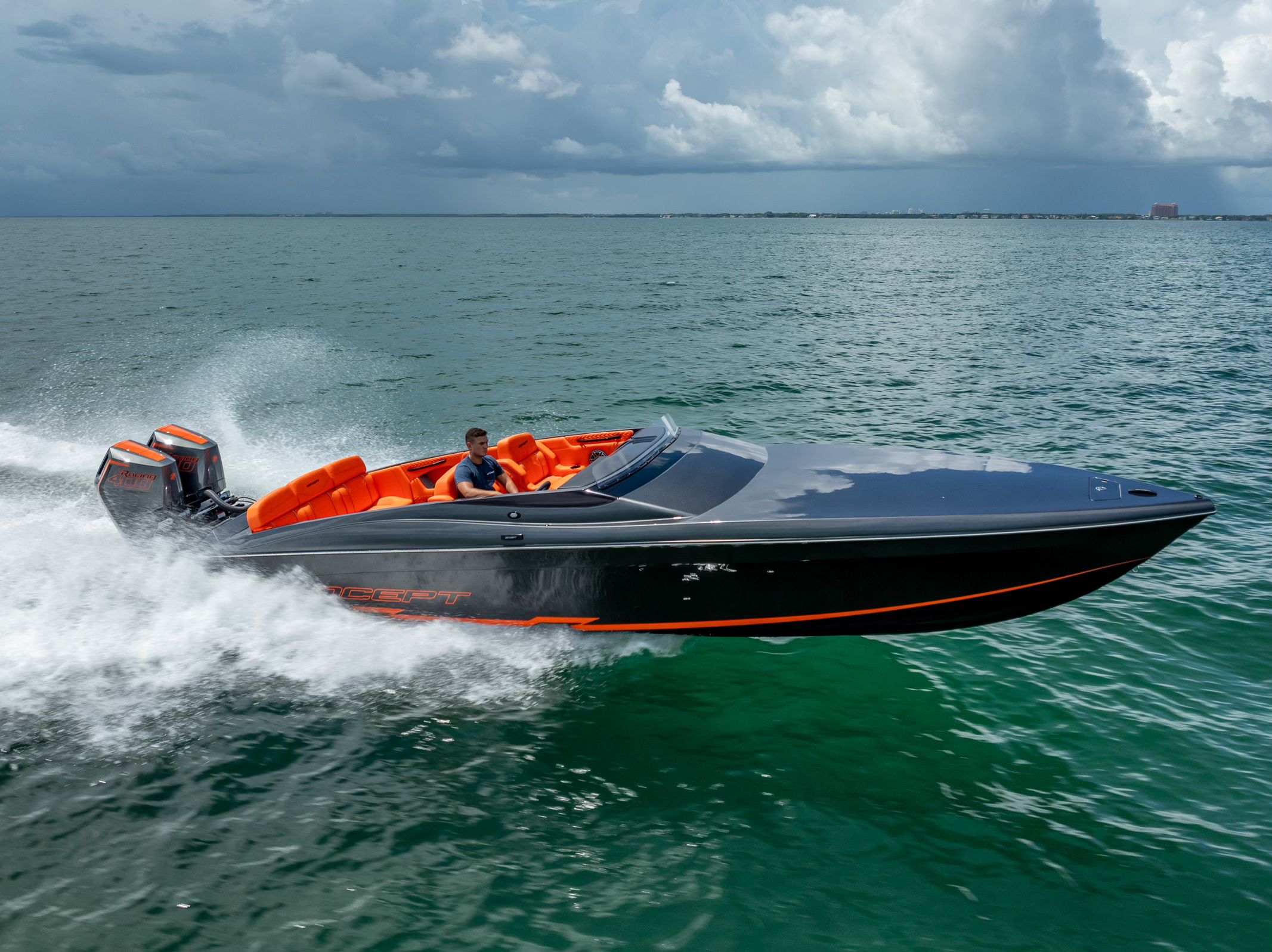 A modern sport boat with orange accents speeds across the water.