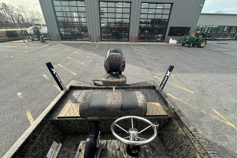 2026 Xpress H190B Bay boat interior with steering wheel and seating, parked outside a building.