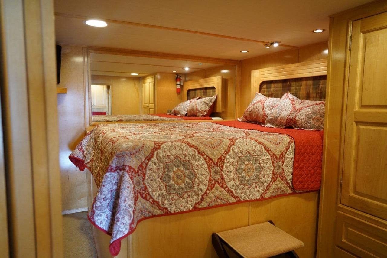 Luxurious bedroom interior of 2000 Stardust Cruisers houseboat, featuring elegant bedding and wood paneling.