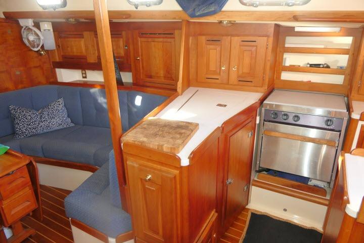 Interior of 2002 Tartan 3700 sailboat with wooden cabinetry and cozy seating area.