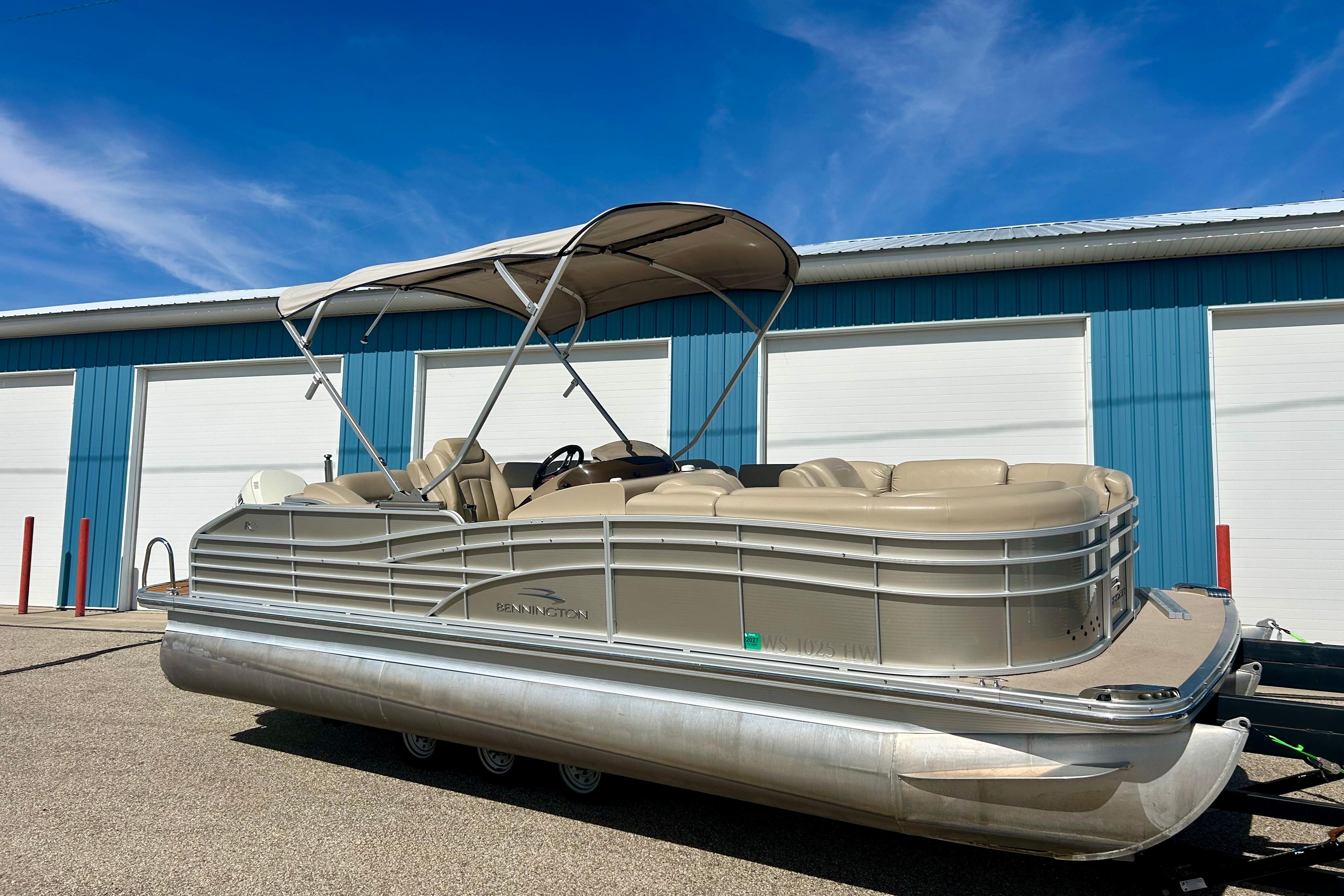2012 Bennington 2250RCL pontoon boat parked outside blue storage units.
