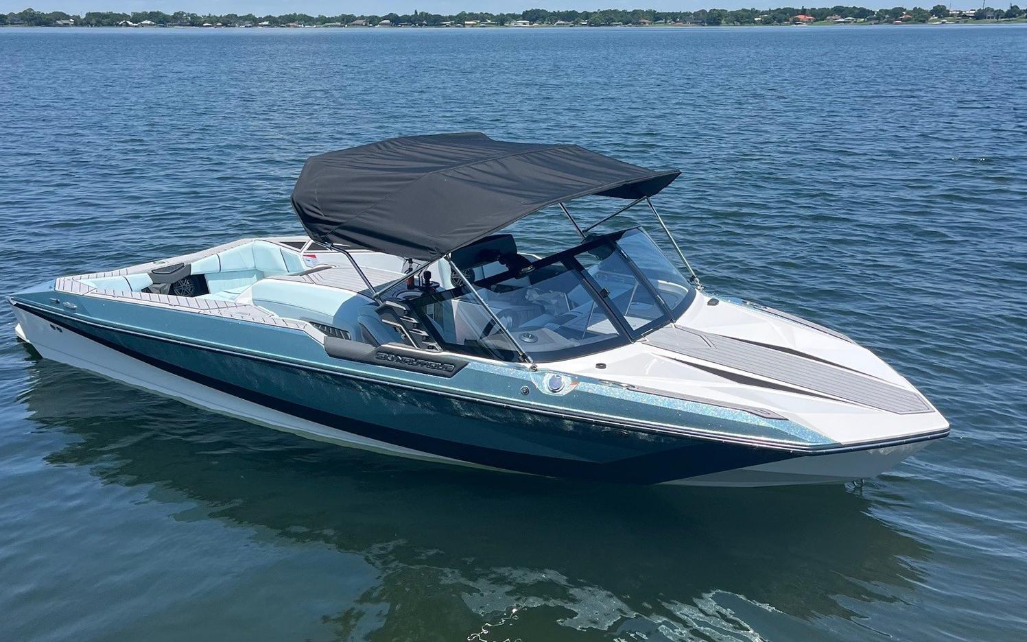 2025 Nautique Ski boat with black canopy on a calm lake.