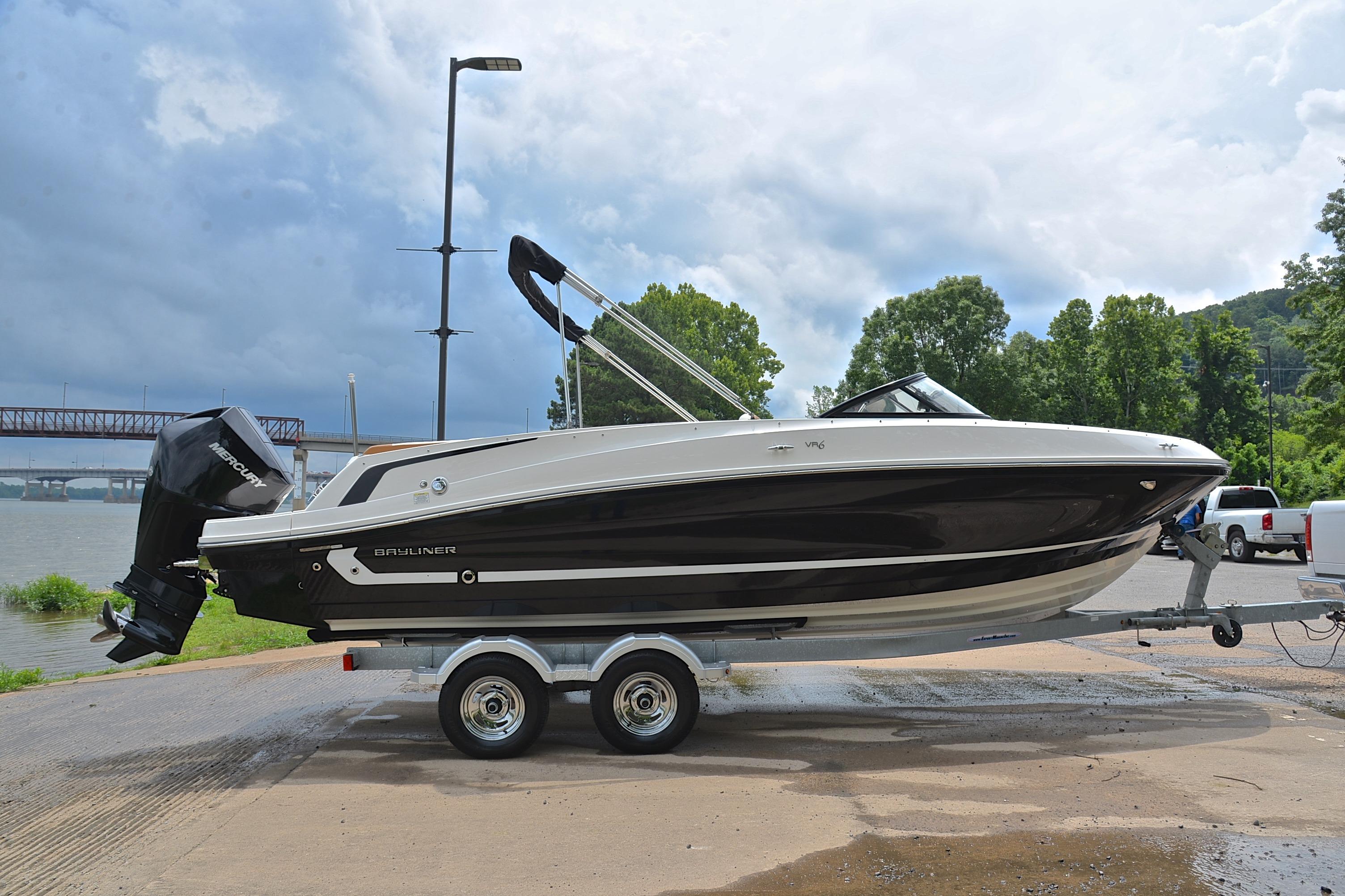 2019 Bayliner VR6 Bowrider OB on trailer by riverside, under cloudy sky.