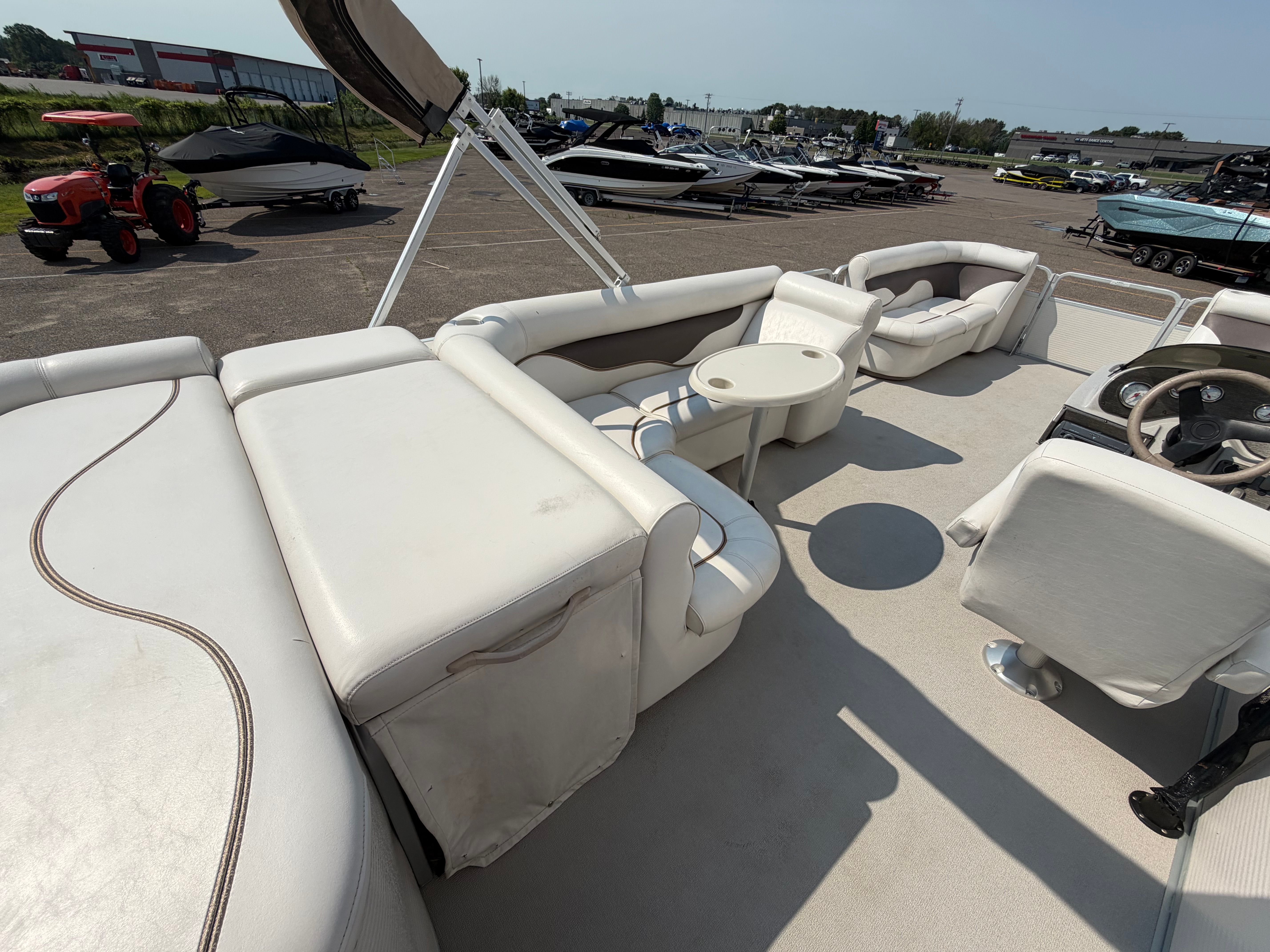 The image shows the deck of a 2007 Premier 225 Sunsation pontoon boat with white seating and a table.