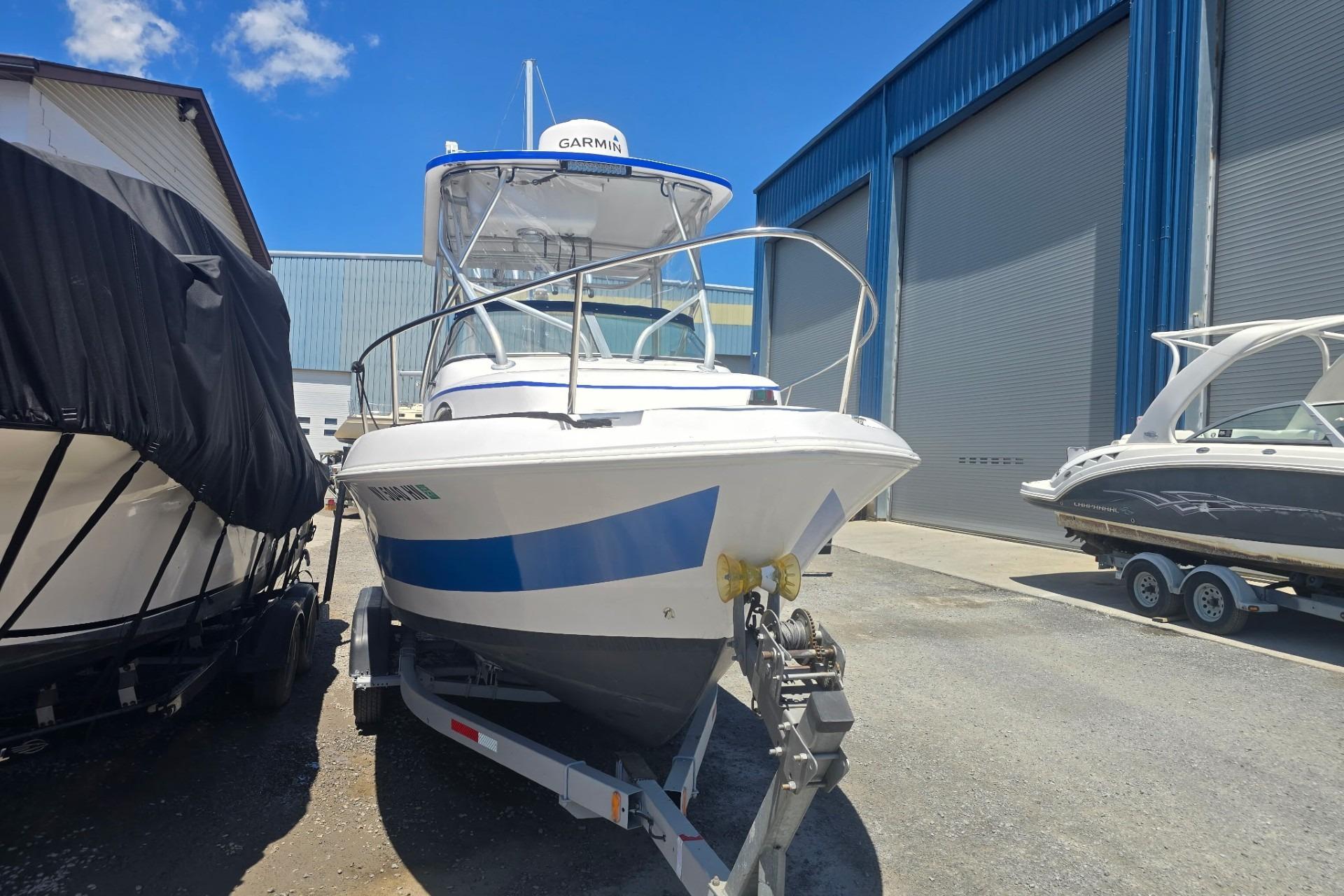 2003 Pro-Line 22 Walkaround boat on trailer, parked near other boats in a marina.