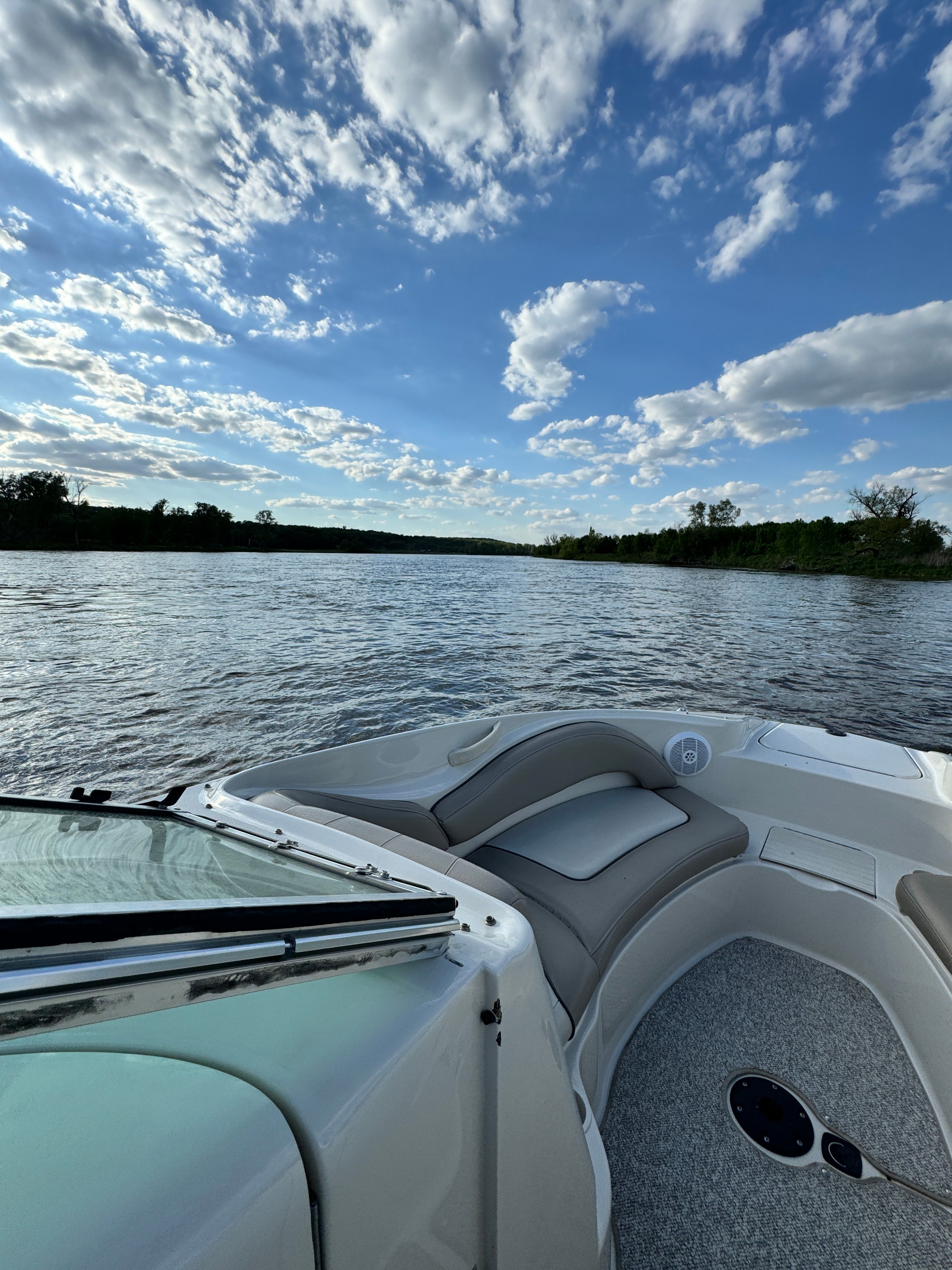 A boat on a calm lake under a cloudy sky.