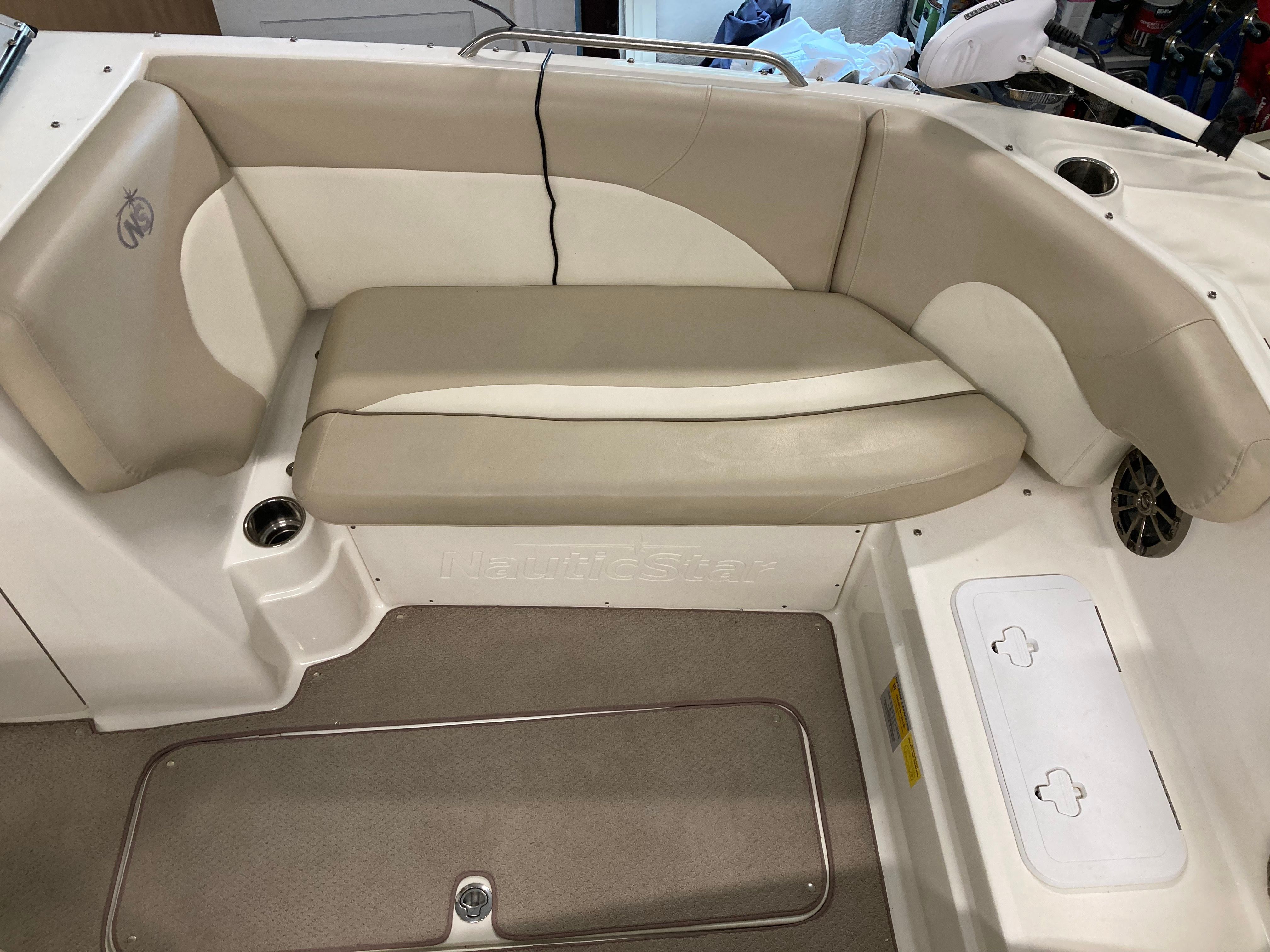 Interior view of a boat with beige seating area and storage.