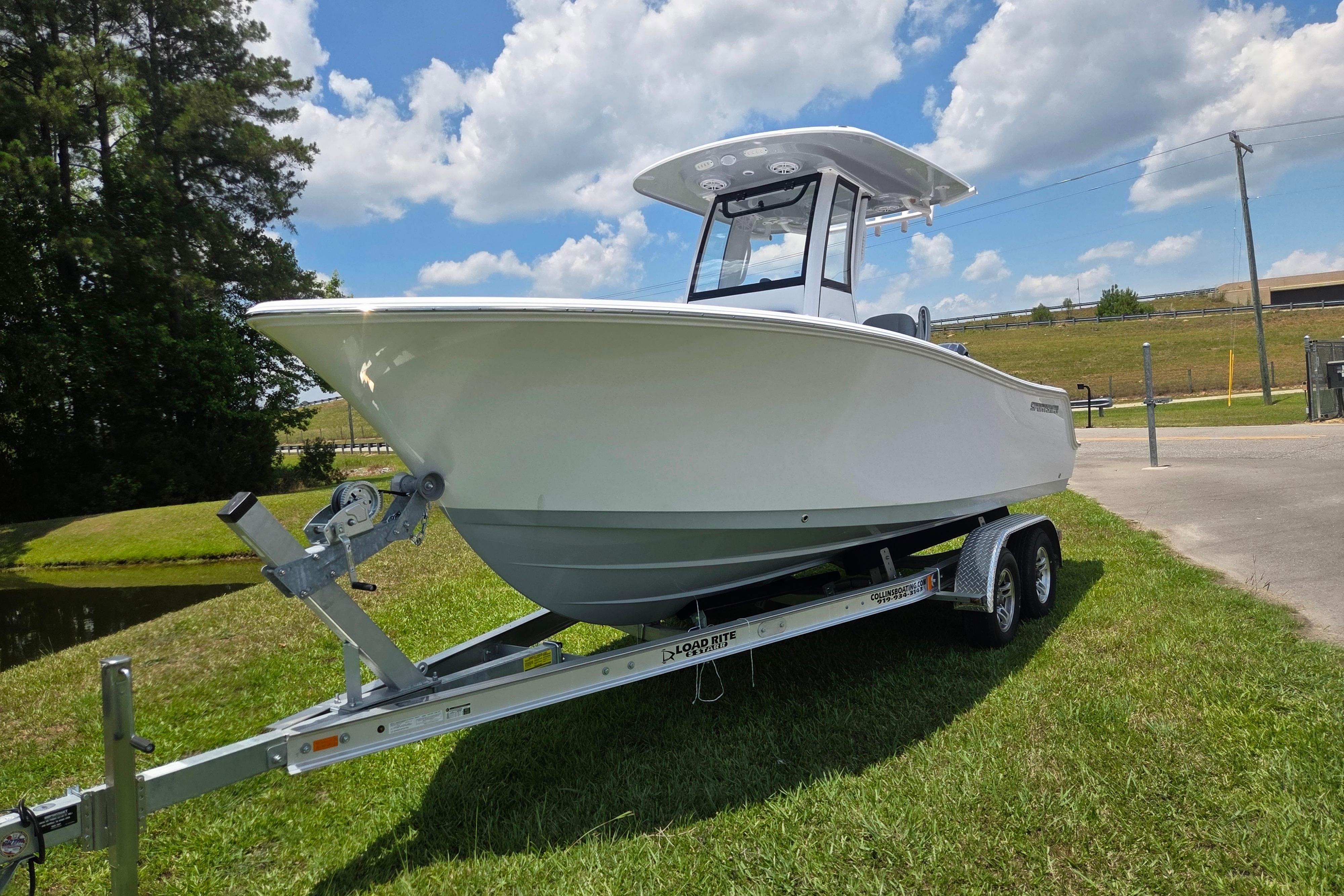 2026 Sportsman Open 212 Center Console boat on trailer, parked on grass under blue sky.