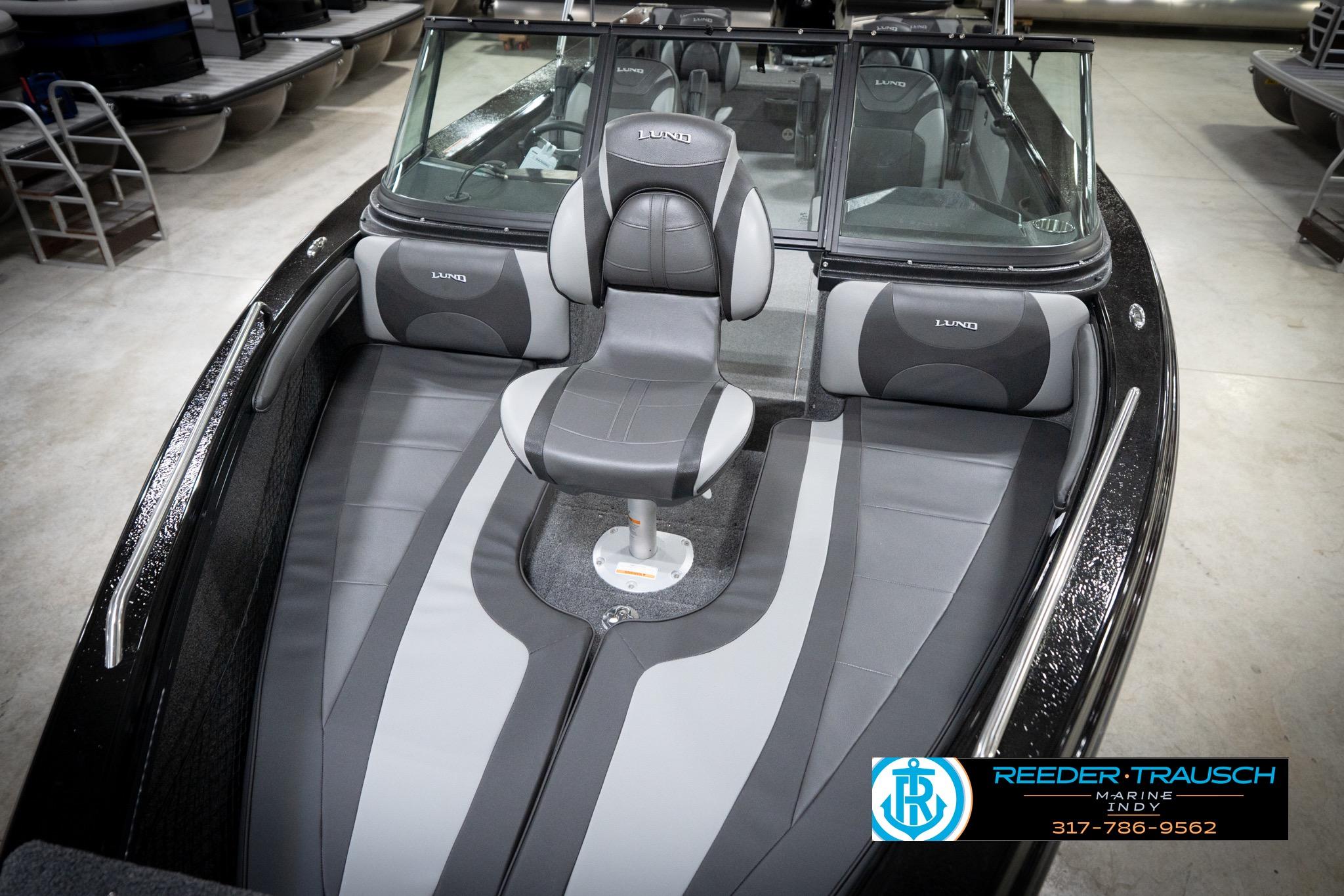 2026 Lund 2275 Baron boat interior with gray seating and windshield in showroom.