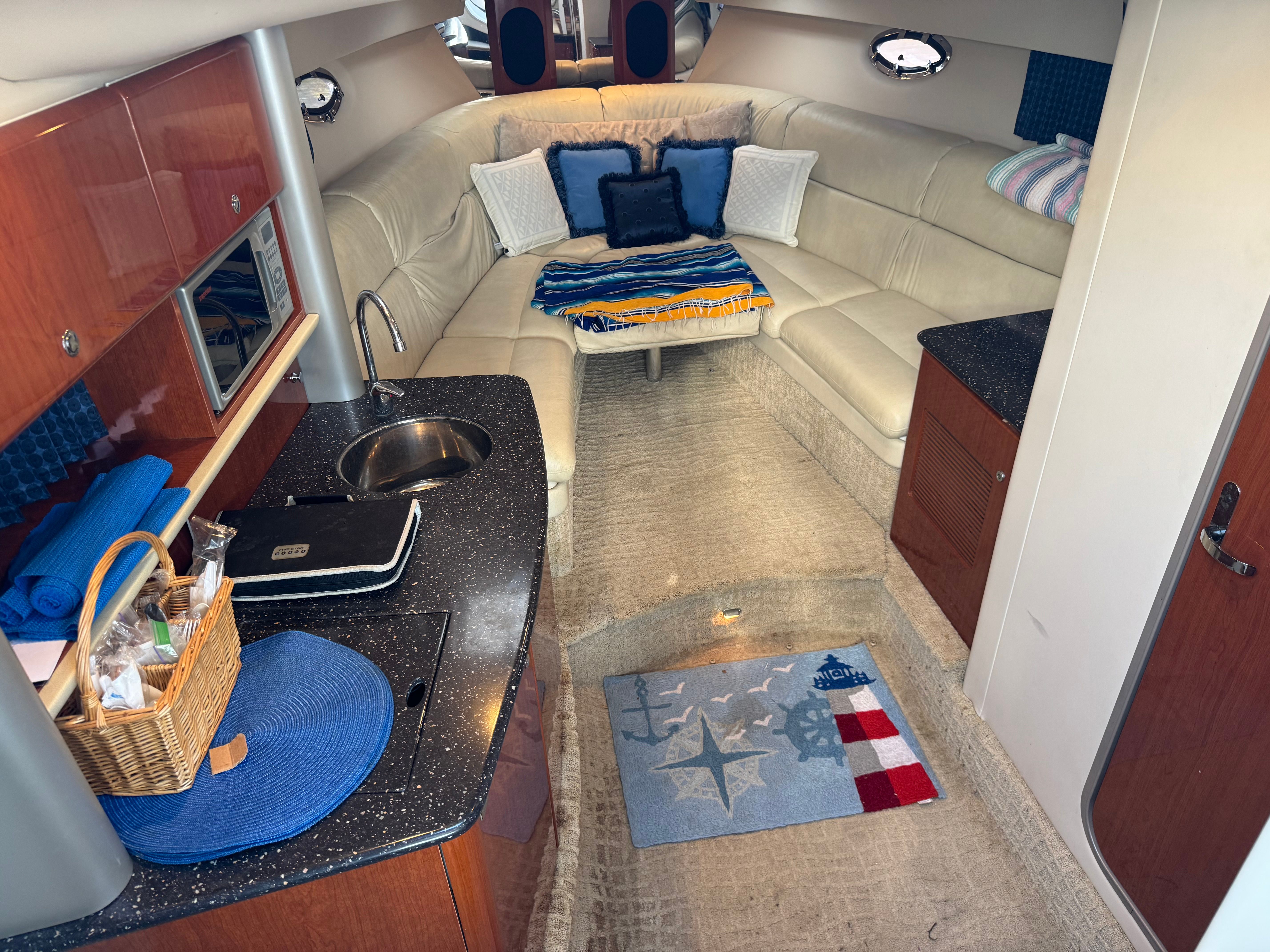 Interior of a yacht with a kitchenette, sofa, and decorative pillows.