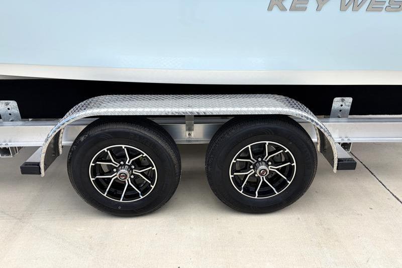 Trailer wheels of 2025 Key West 210 Bay Reef boat on concrete surface.