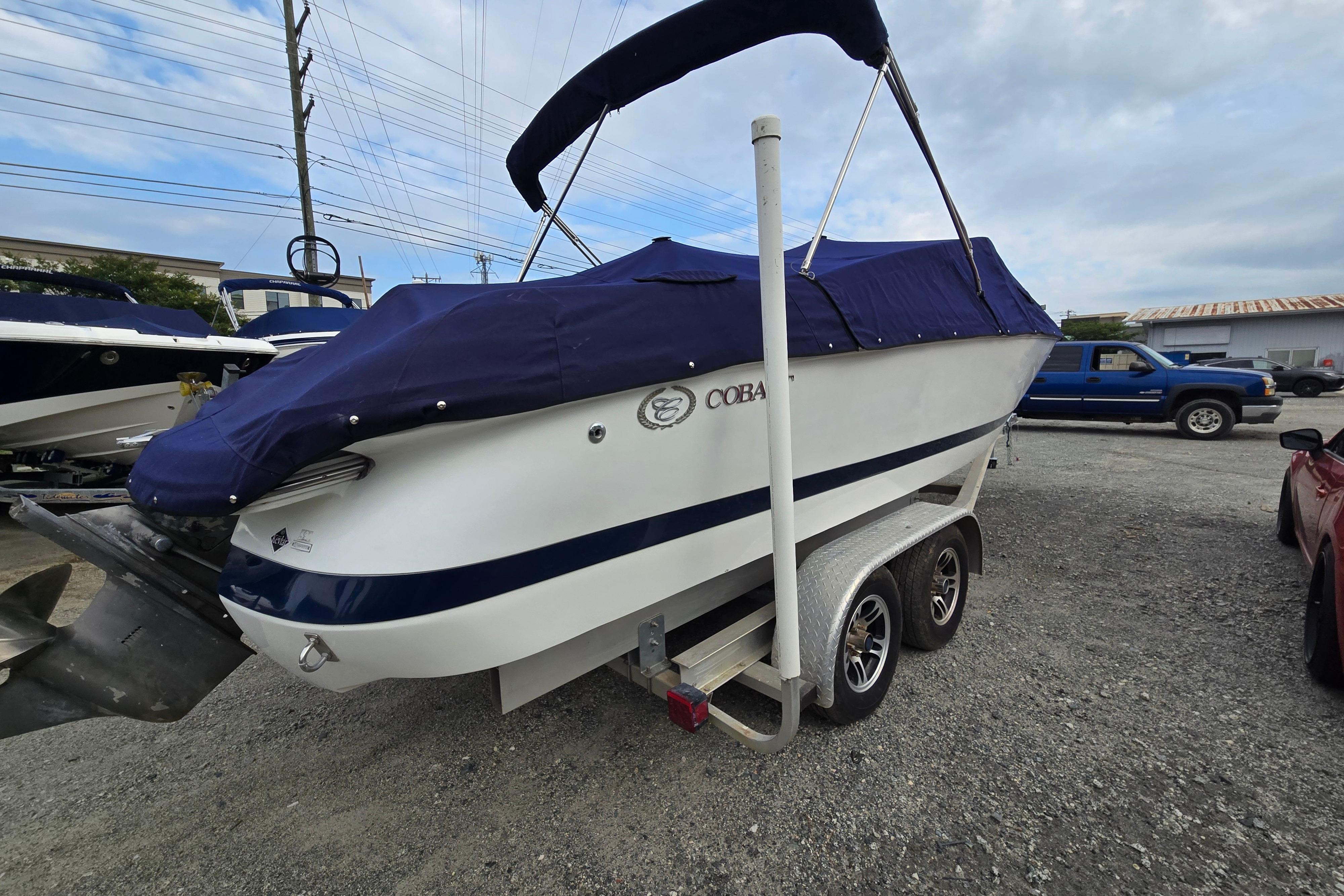 Covered 2000 Cobalt 246 boat on trailer, parked outdoors under cloudy sky.