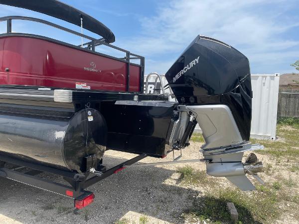 2023 Regency 250 DL3 pontoon boat with Mercury outboard motor, parked on gravel.