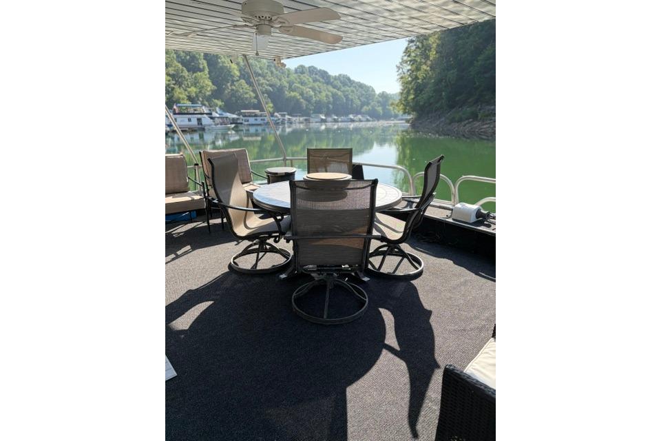 Outdoor seating on 1997 Stardust Houseboat 18x83, overlooking serene lake and lush greenery.