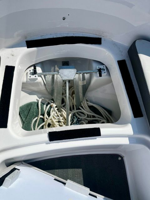 An open storage compartment with an anchor and ropes on a Yamaha SX190 boat.