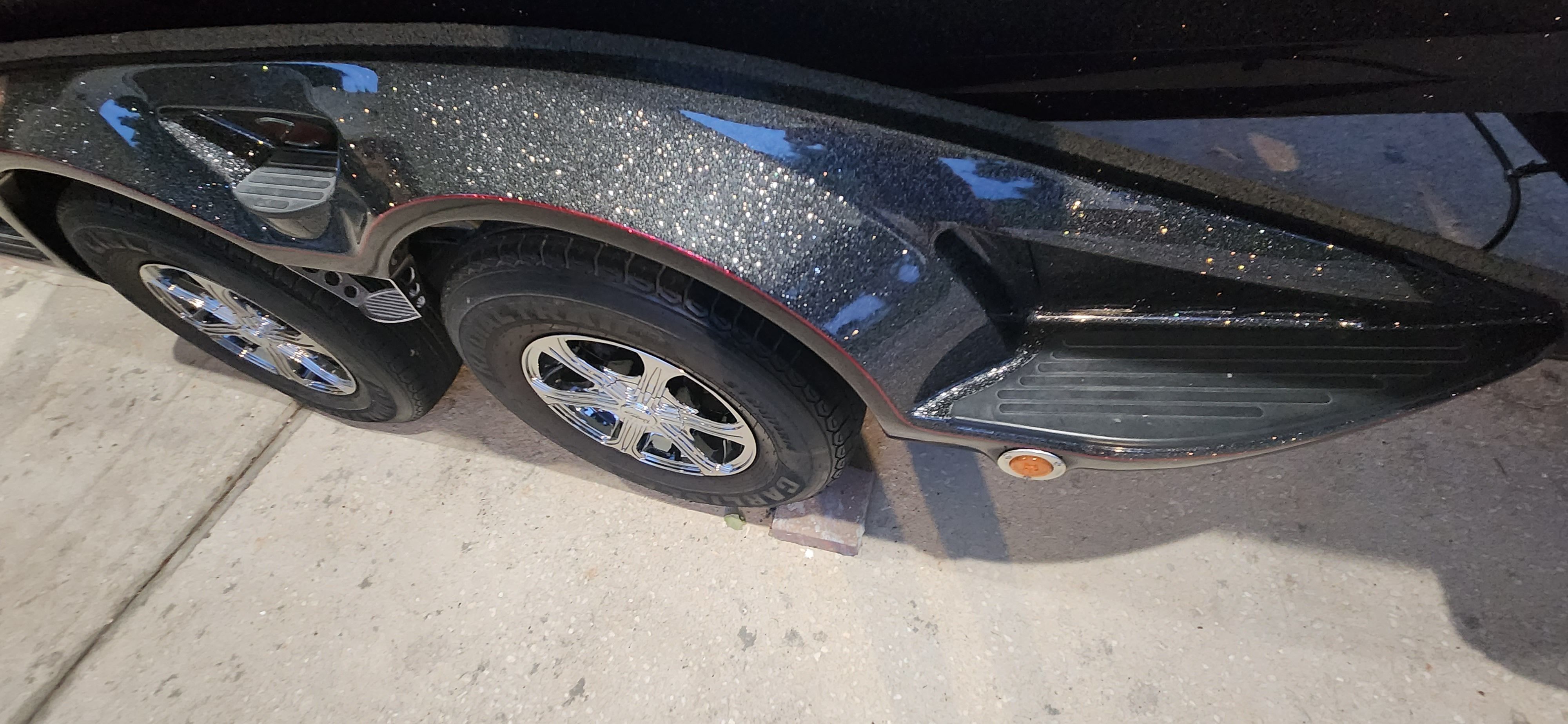 Close-up of a boat trailer with two wheels and a shiny surface.