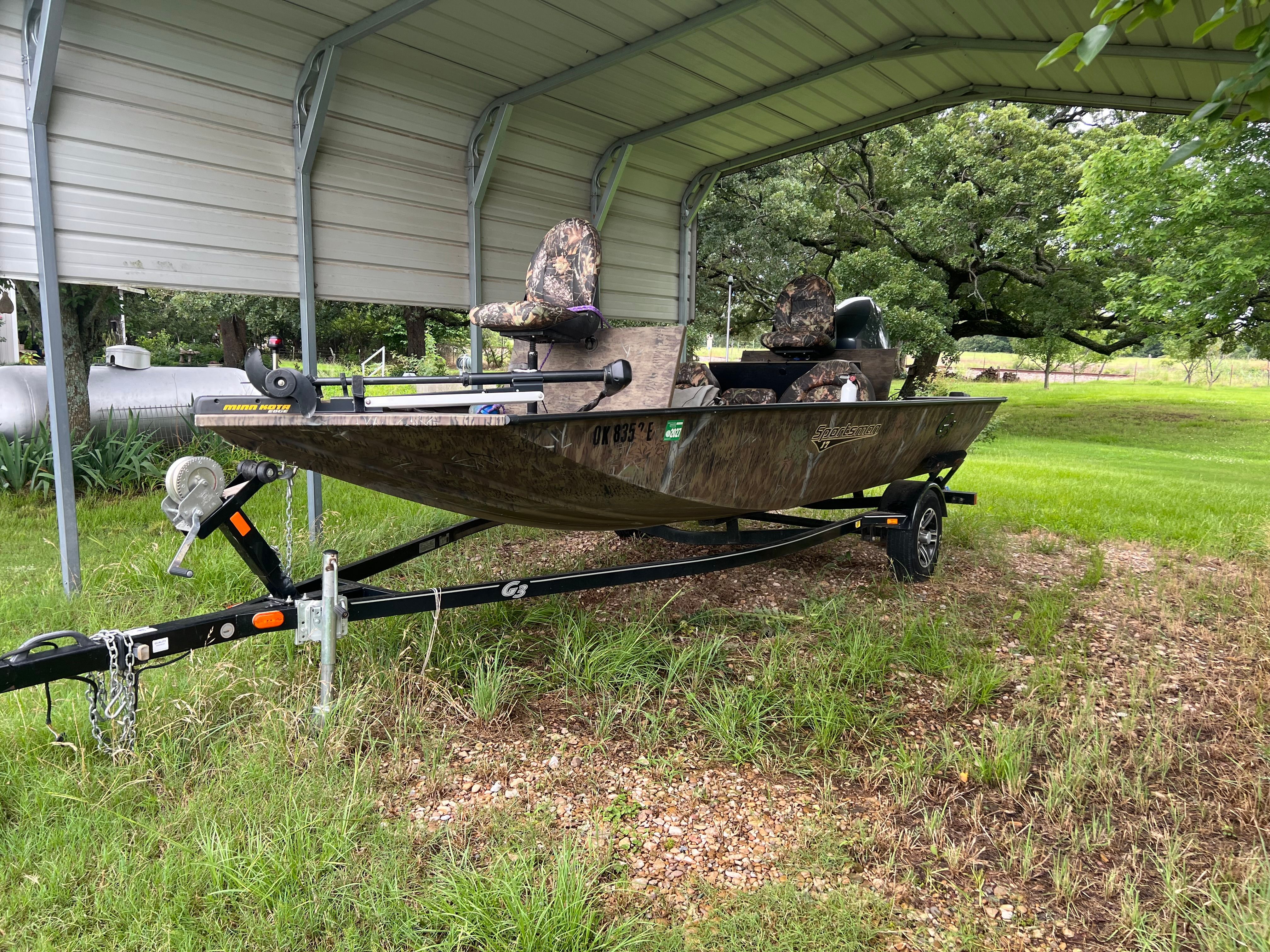 A 2017 G3 Sportsman 17 Camo boat on a trailer under a metal shelter.