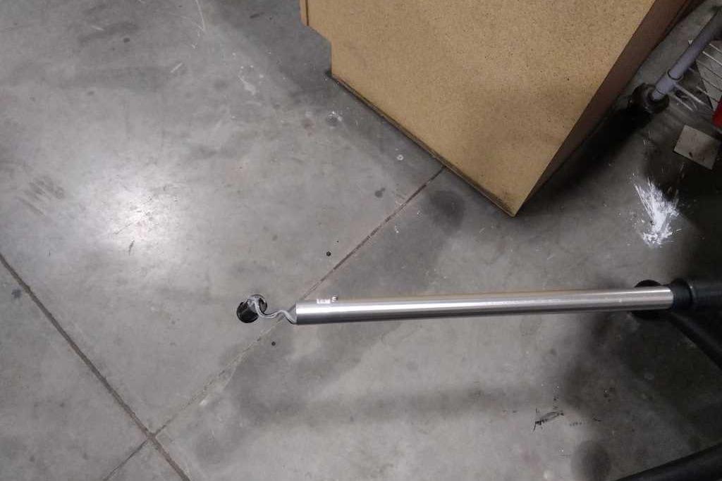 A metal pole with a small wheel on a concrete floor.