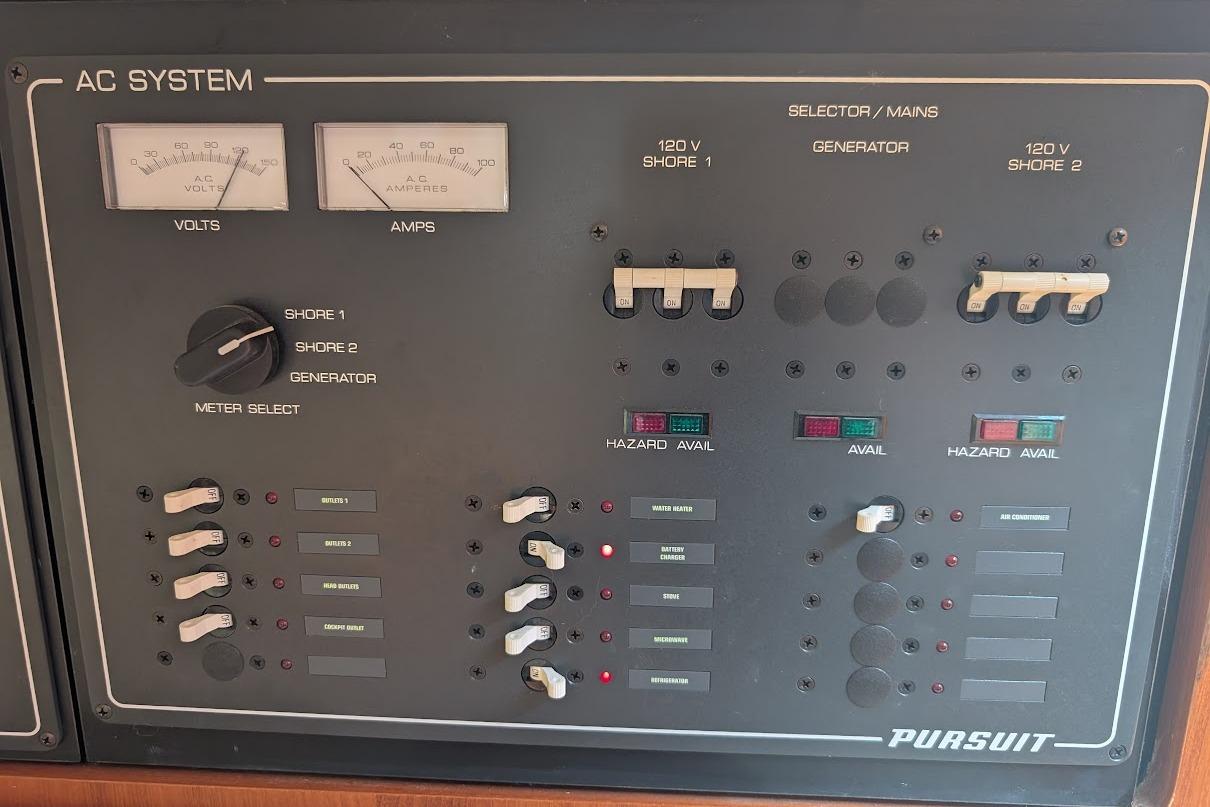 Control panel of a 2000 Pursuit 3400 Express boat, featuring AC system gauges and switches.