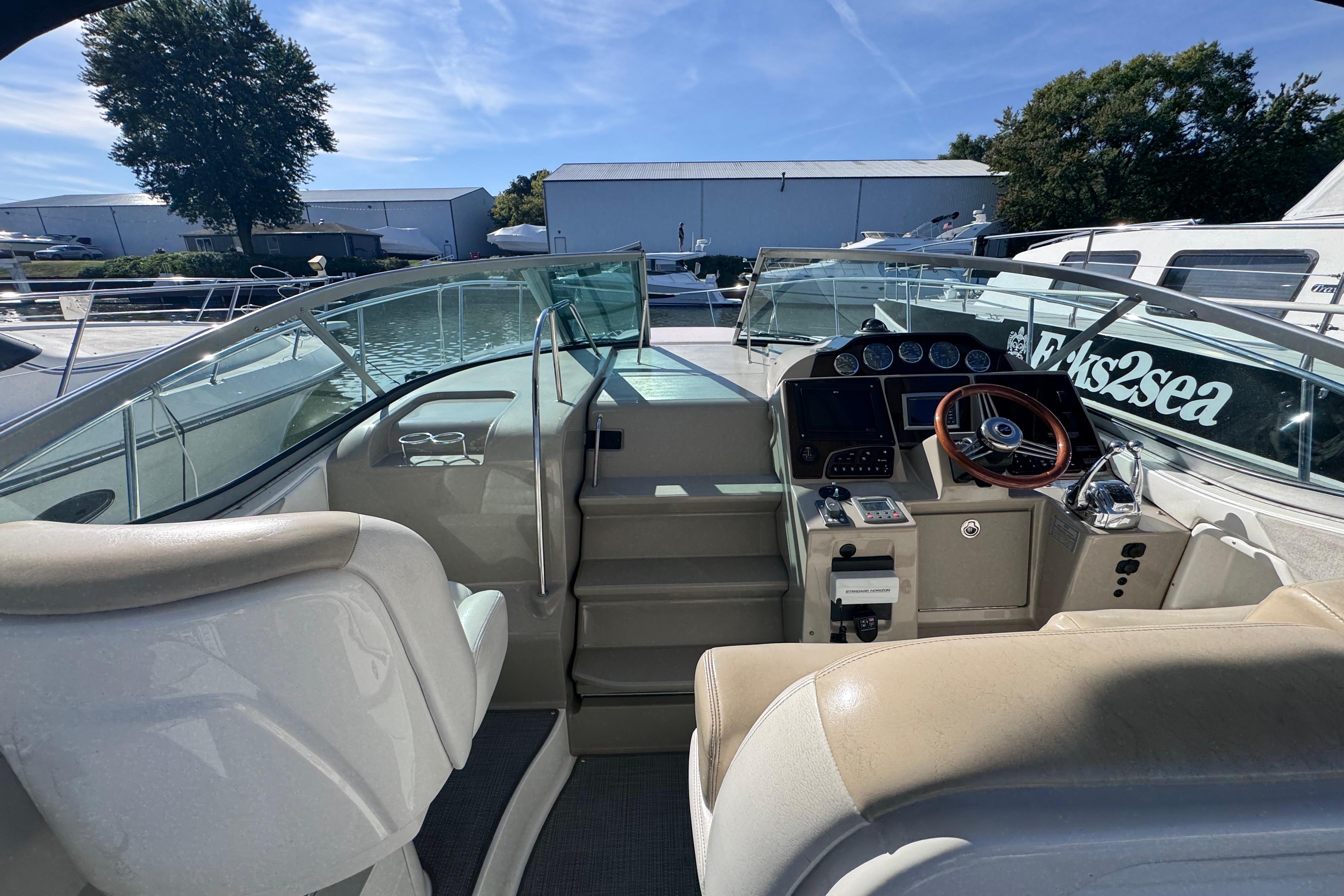 2008 Sea Ray 350 Sundancer cockpit with steering wheel and control panel, docked under clear sky.