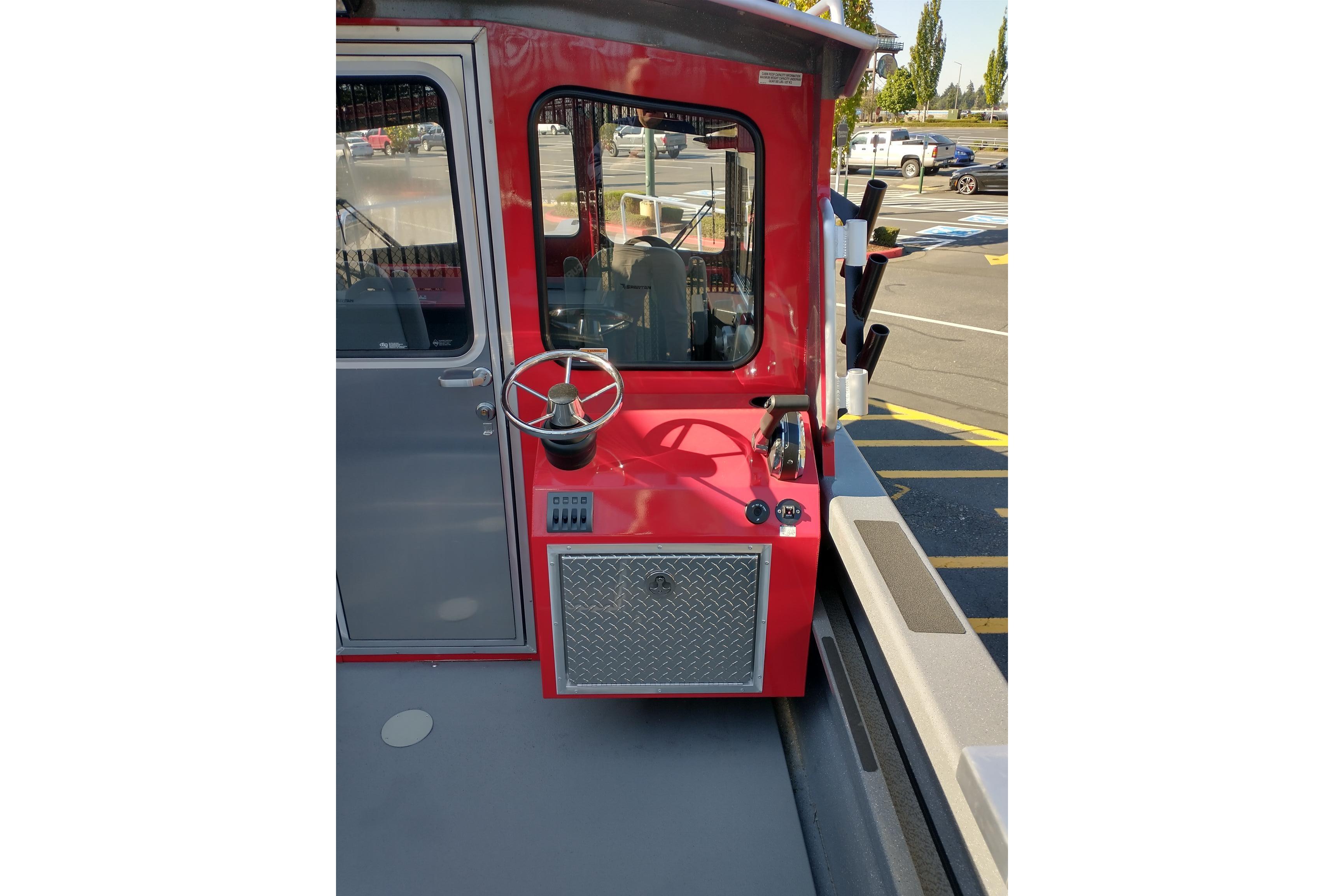 Red 2024 Spartan 220 Maximus Pro boat helm with steering wheel and control panel.