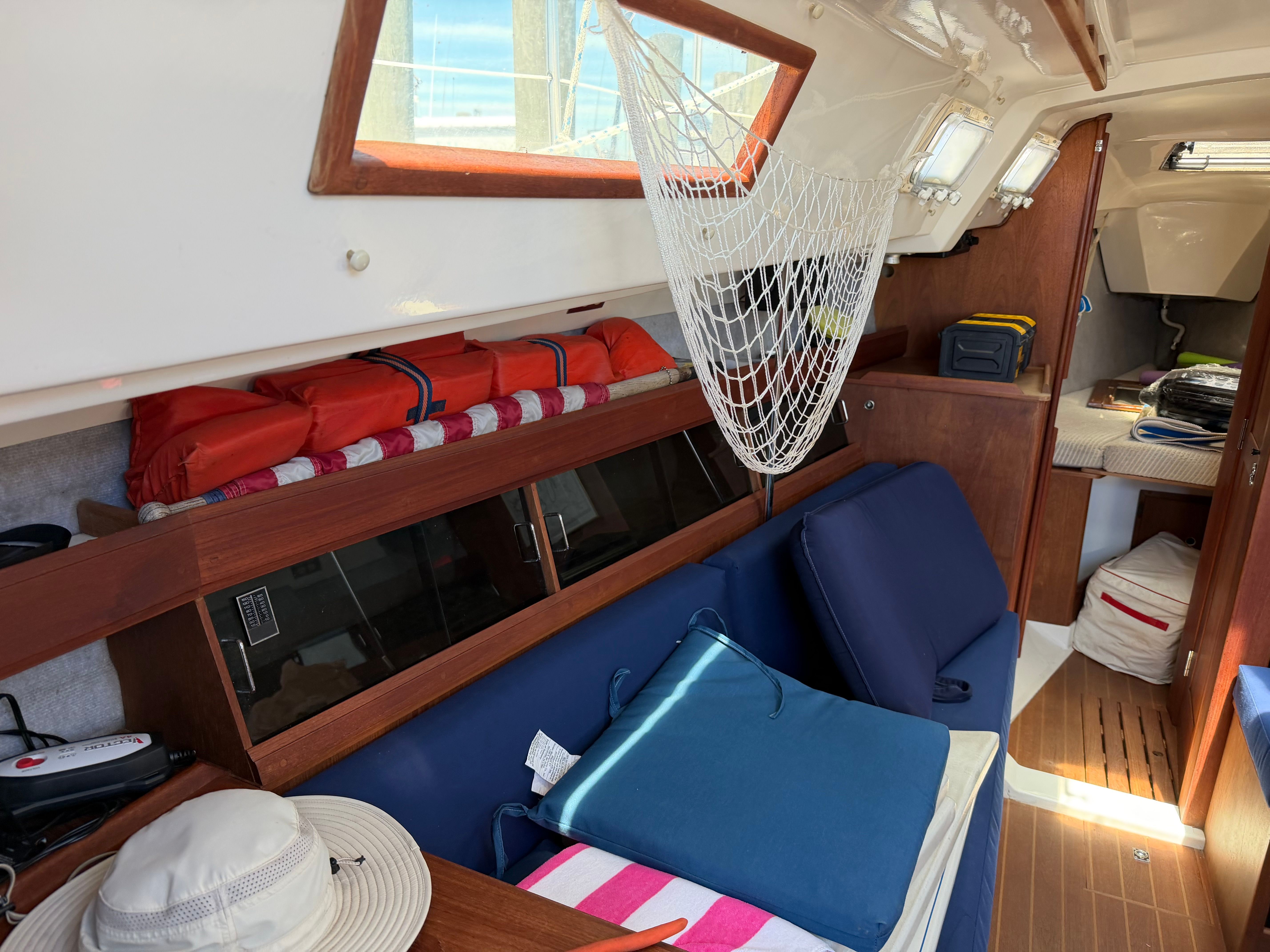 Interior of a sailboat with blue cushions and a hammock.
