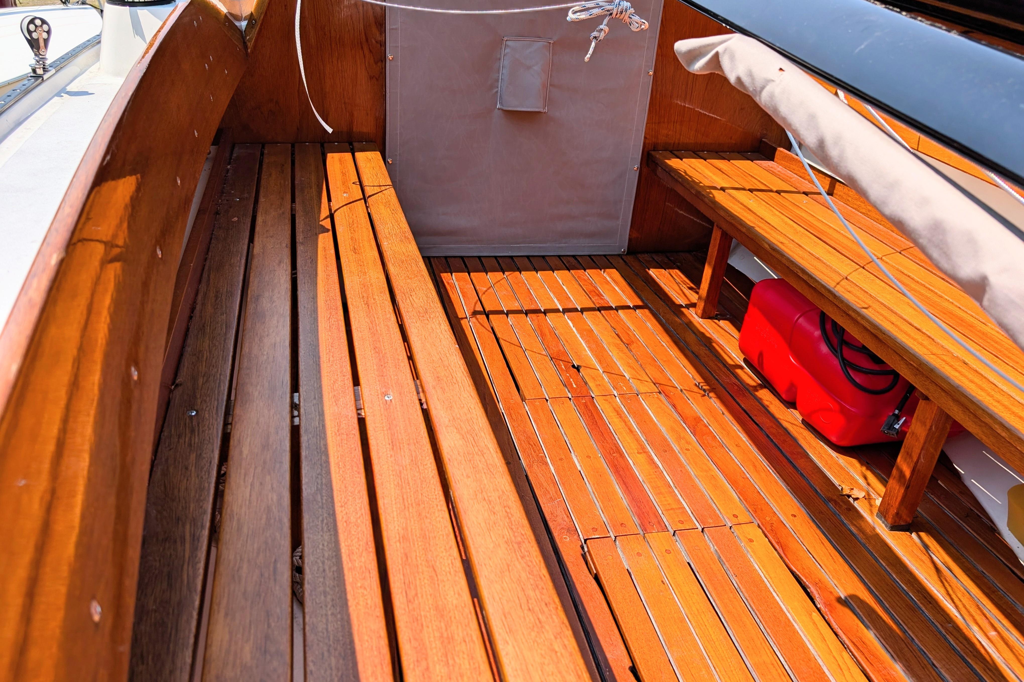 Interior of a 1965 Pearson Ensign sailboat with polished wooden flooring and seating.