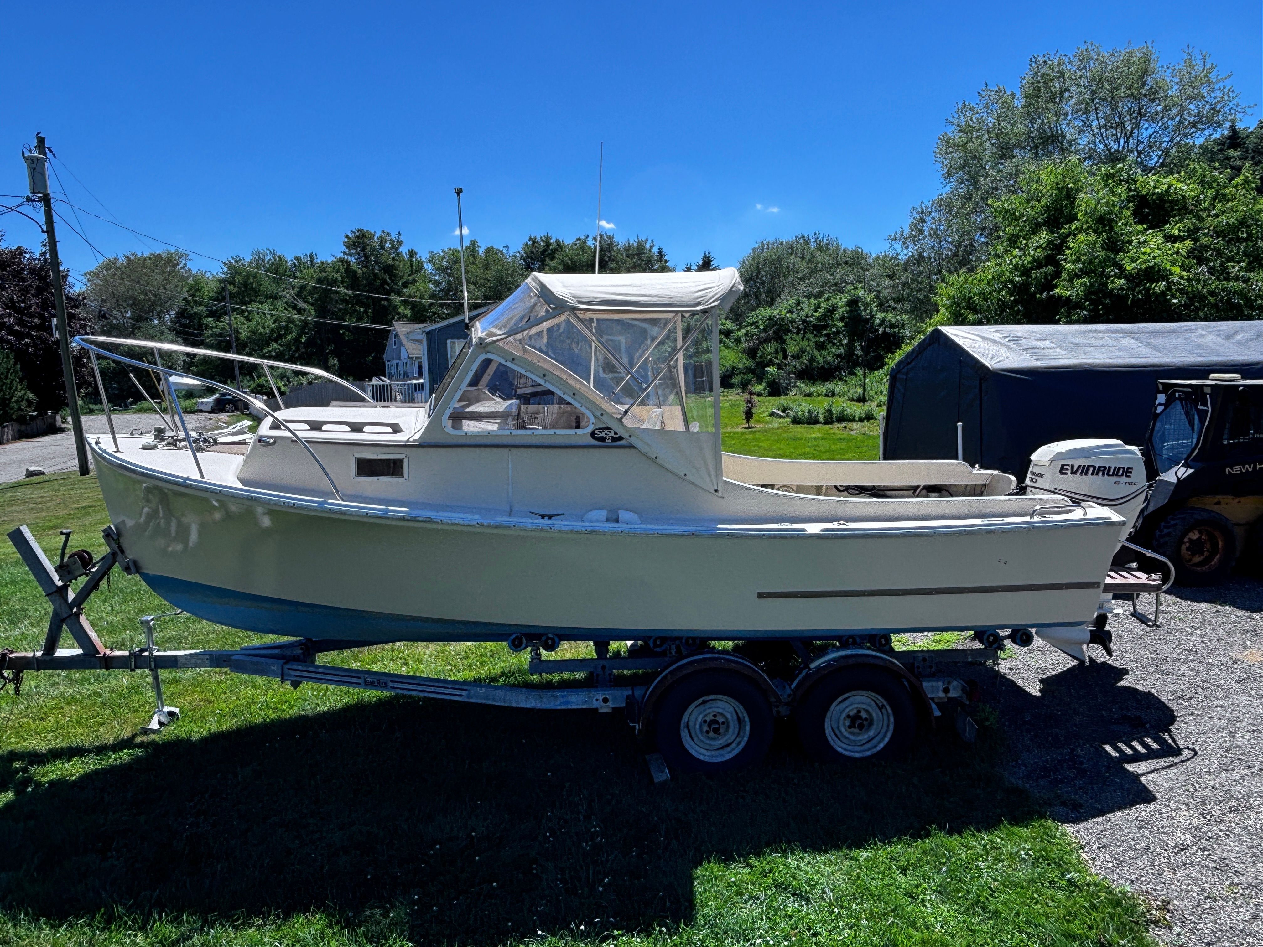 A 1984 SISU 22’ Bass boat on a trailer, surrounded by trees and a blue sky.