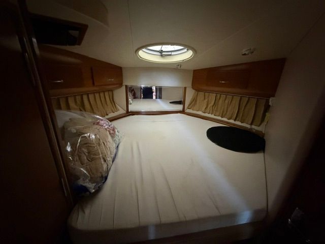 Interior of a yacht with a large bed and wooden cabinets.